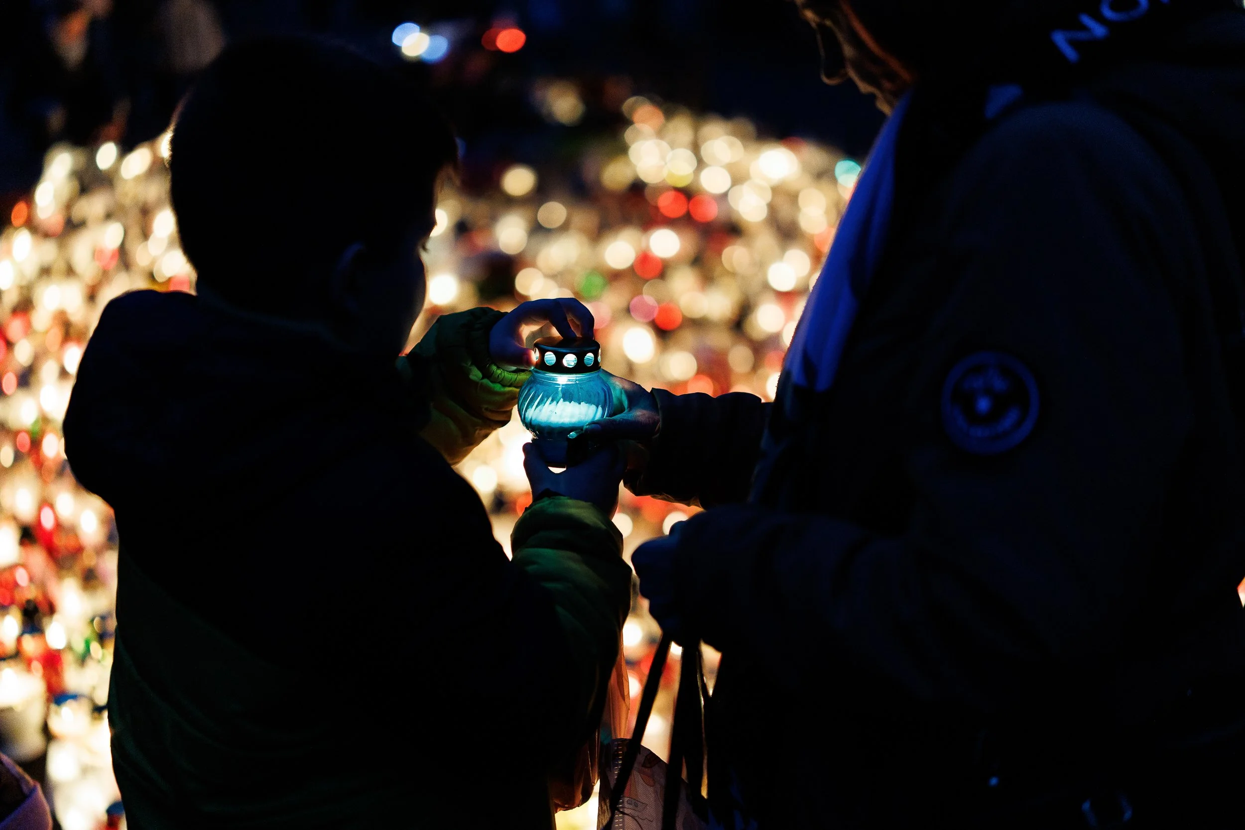 People placing candles under the Iron Cross in memory of the victims of the Franco-Prussian War of 1870-1871, All Saints' Day, Central Cemetery, Szczecin, Poland, November 1, 2025