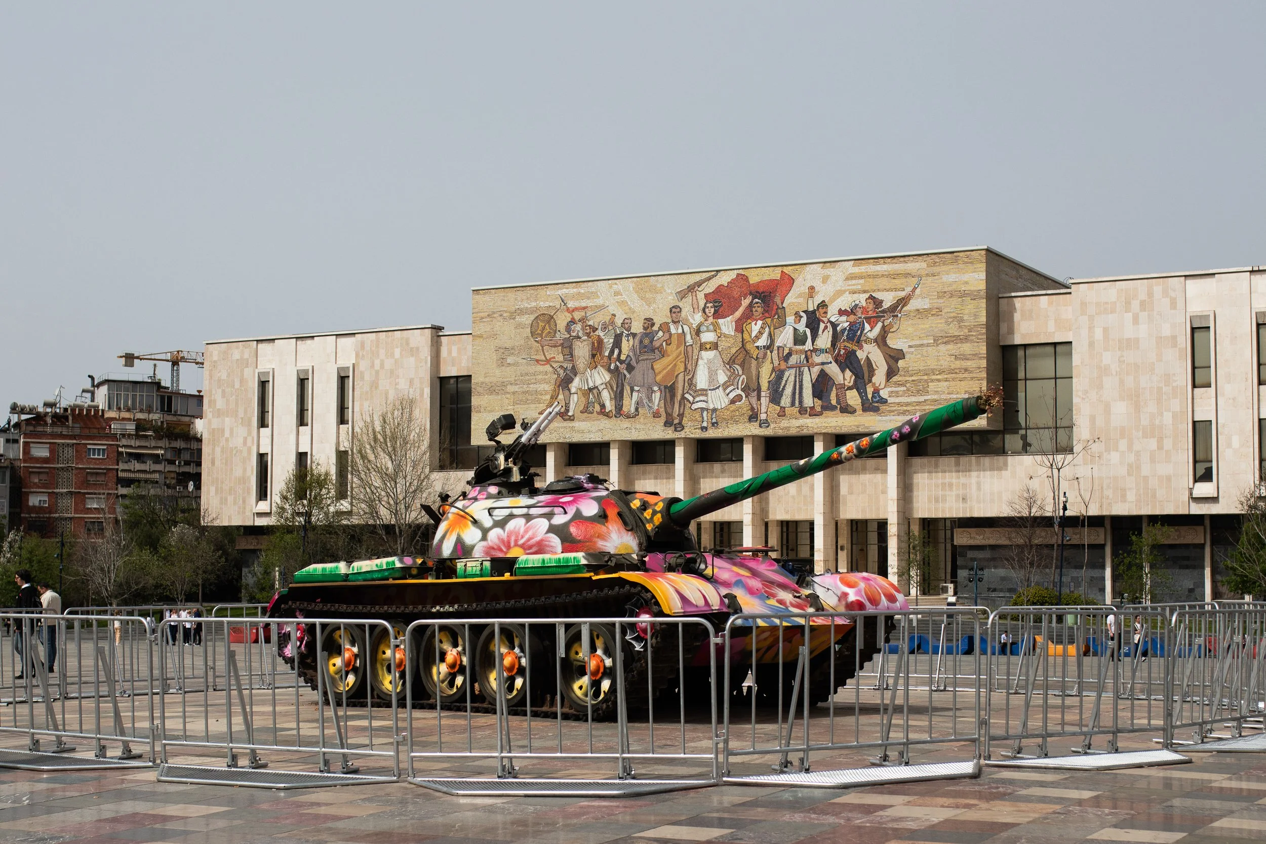 A tank painted in contrasting colors with flowers in its barrel stands in front of the National Historical Museum, Tirana, Albania, March 31, 2024