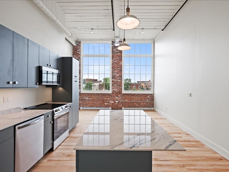 The Spinning Mill - Bright kitchen with stainless steel appliances, ceiling fan, and hardwood floors