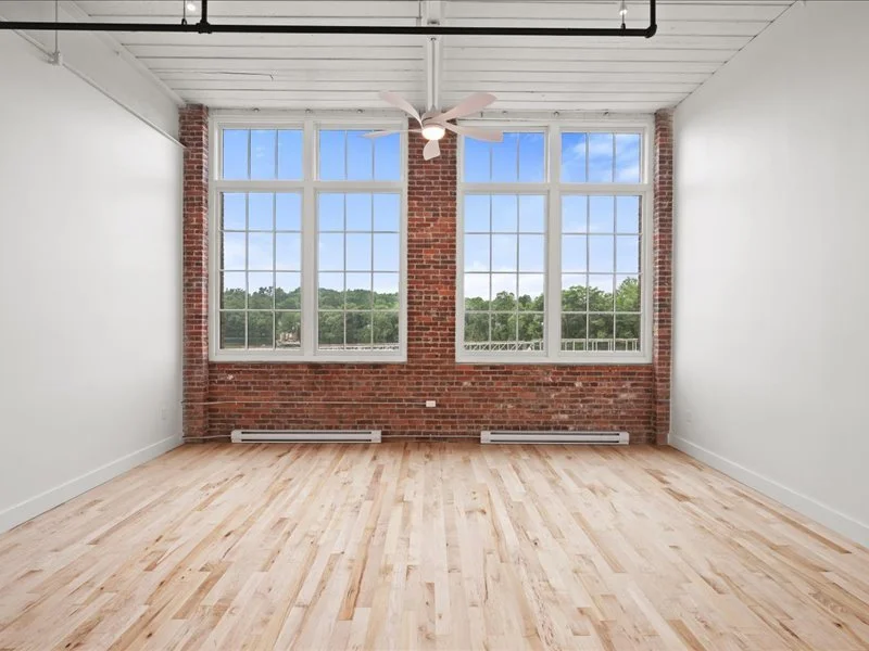 The Spinning Mill - Spacious living area with exposed brick walls, tall windows, and natural light