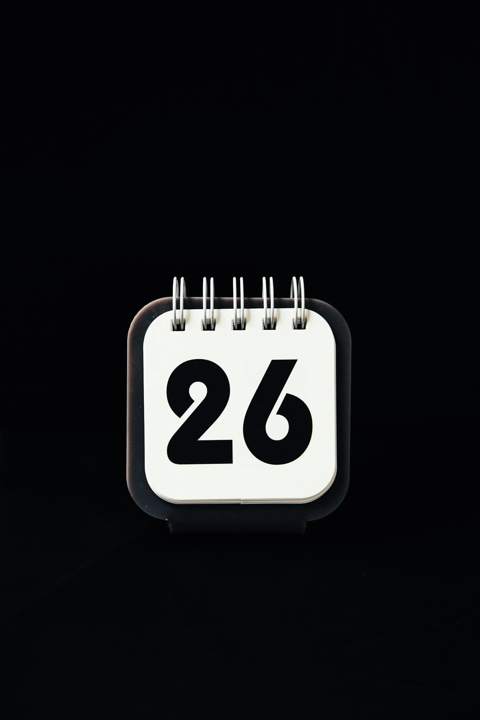 A flip calendar displaying the number 26, set against a black background.