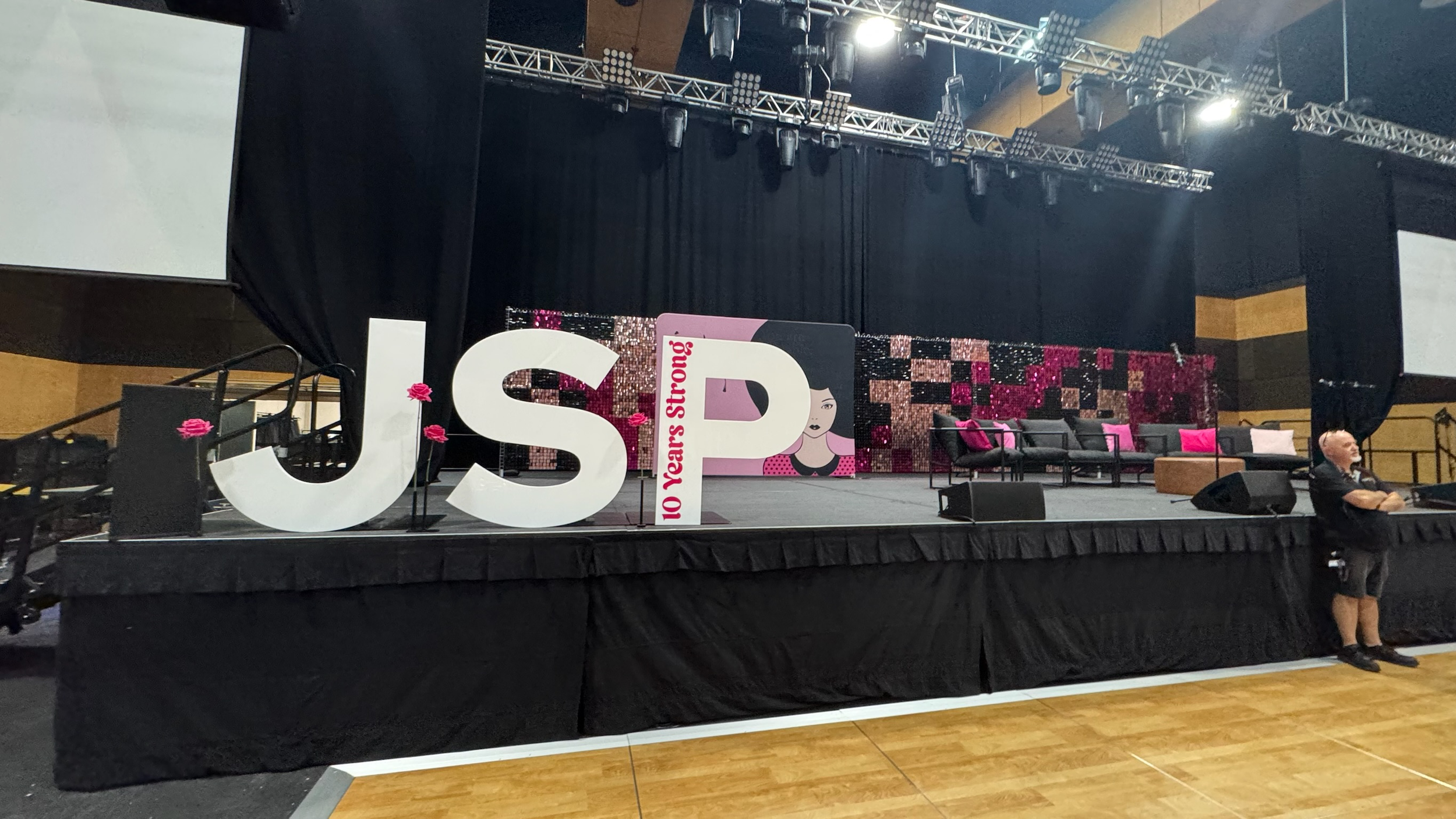 Stage set up with large white J and S letters, a banner with 