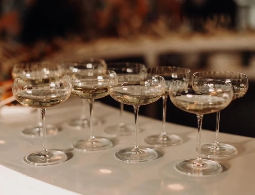 Several empty champagne coupe glasses arranged on a white surface.