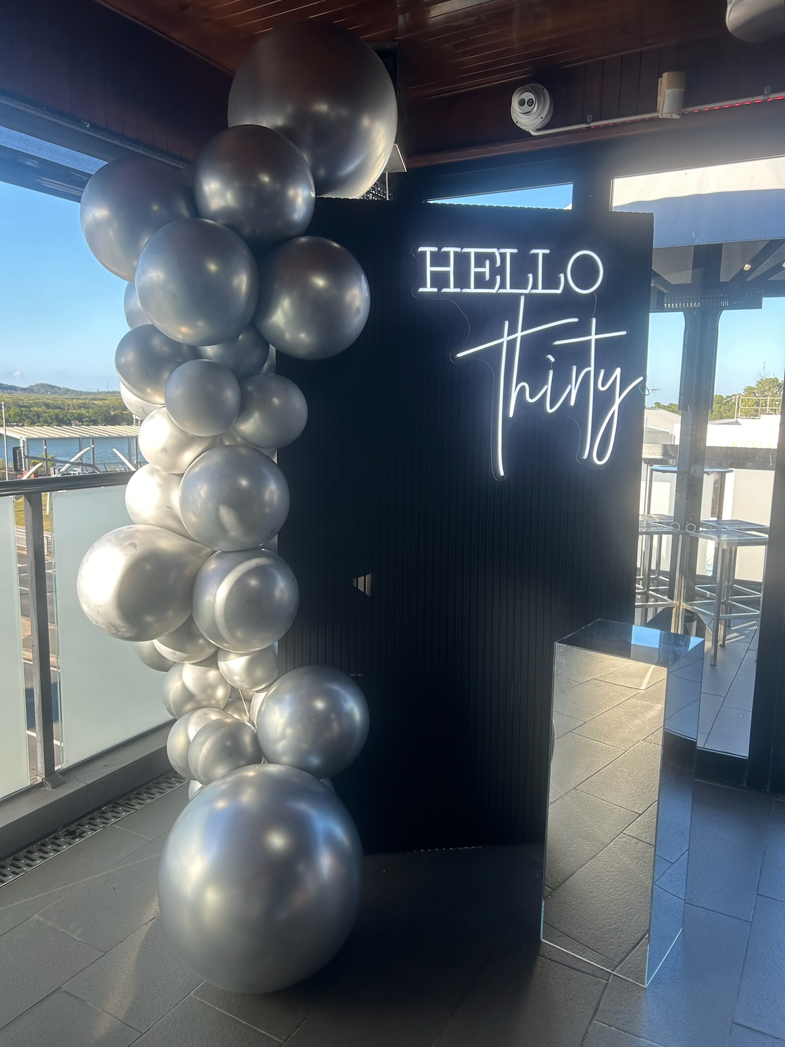 Decorative display with black and silver balloons and a sign that says 'Hello Thirty' in a modern font.