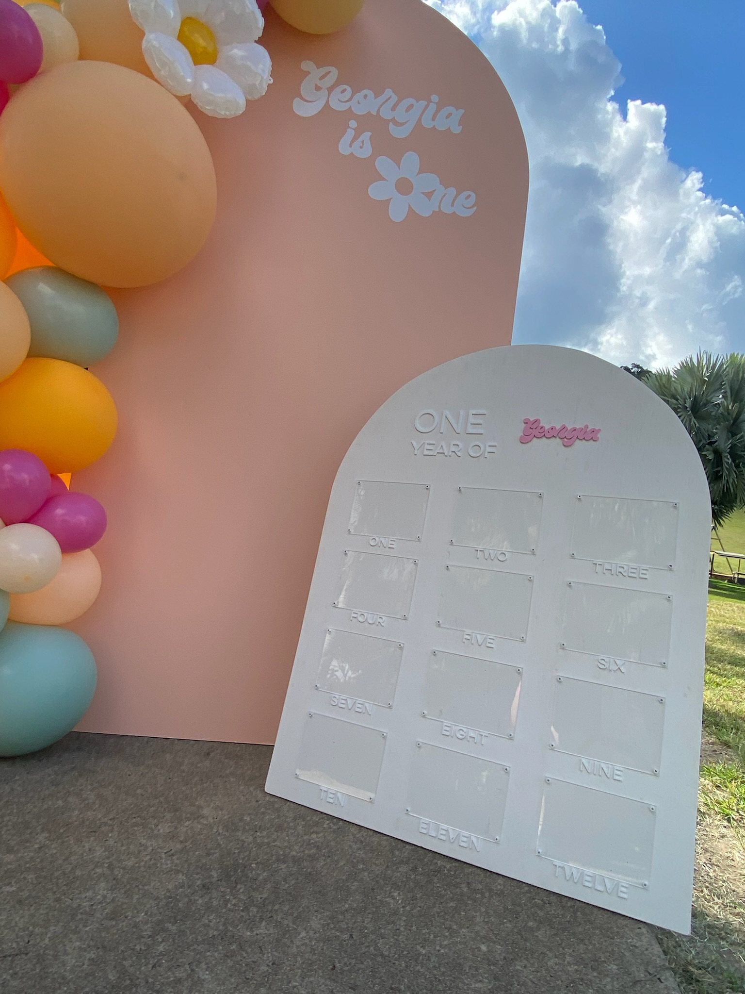 Decorative display celebrating Georgia's first year, featuring a pink backdrop with balloons and a white board with numbered sections for counting.