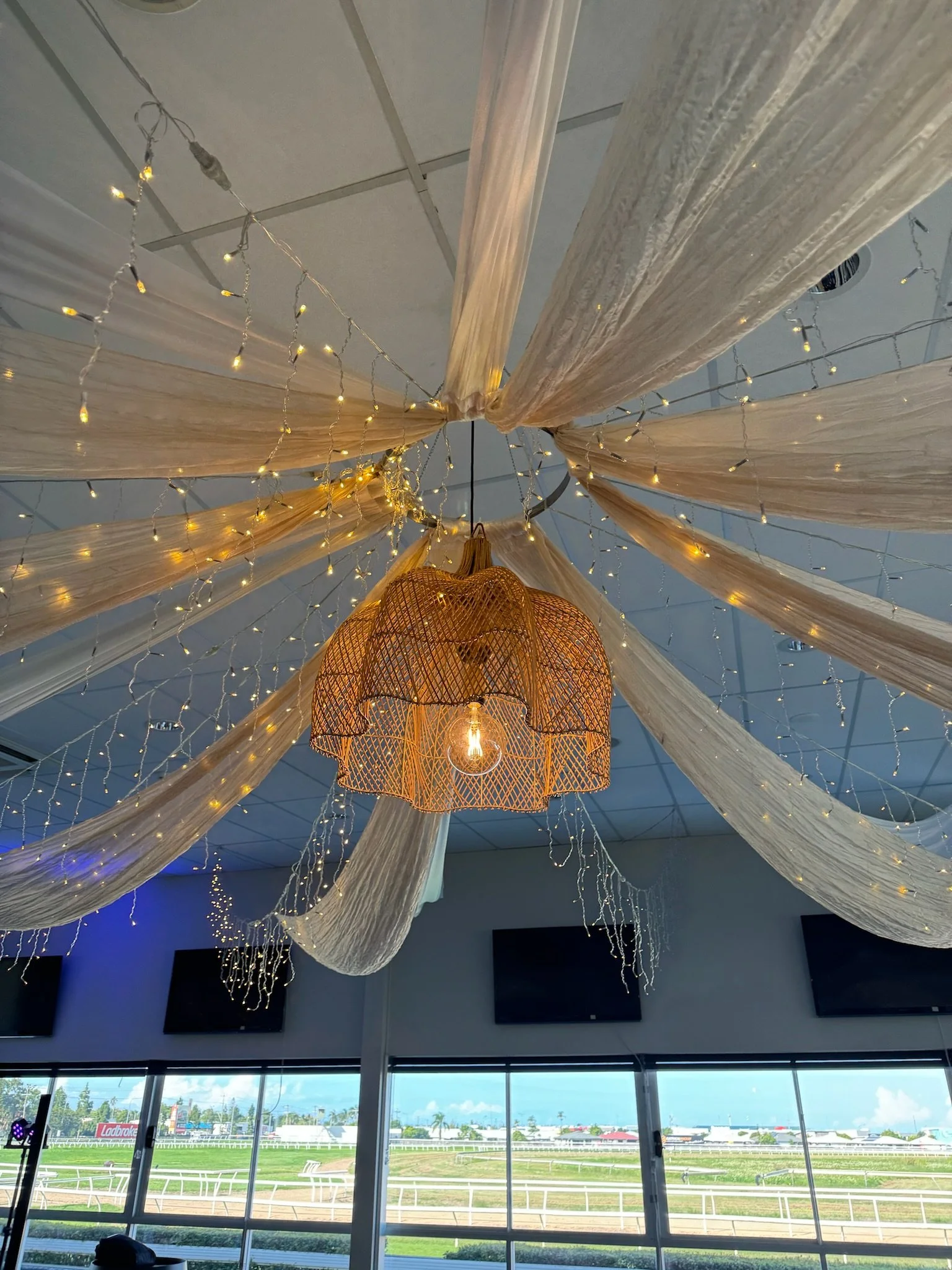Decorative ceiling with draped fabric, string lights, and a hanging wicker lantern with an exposed lightbulb.