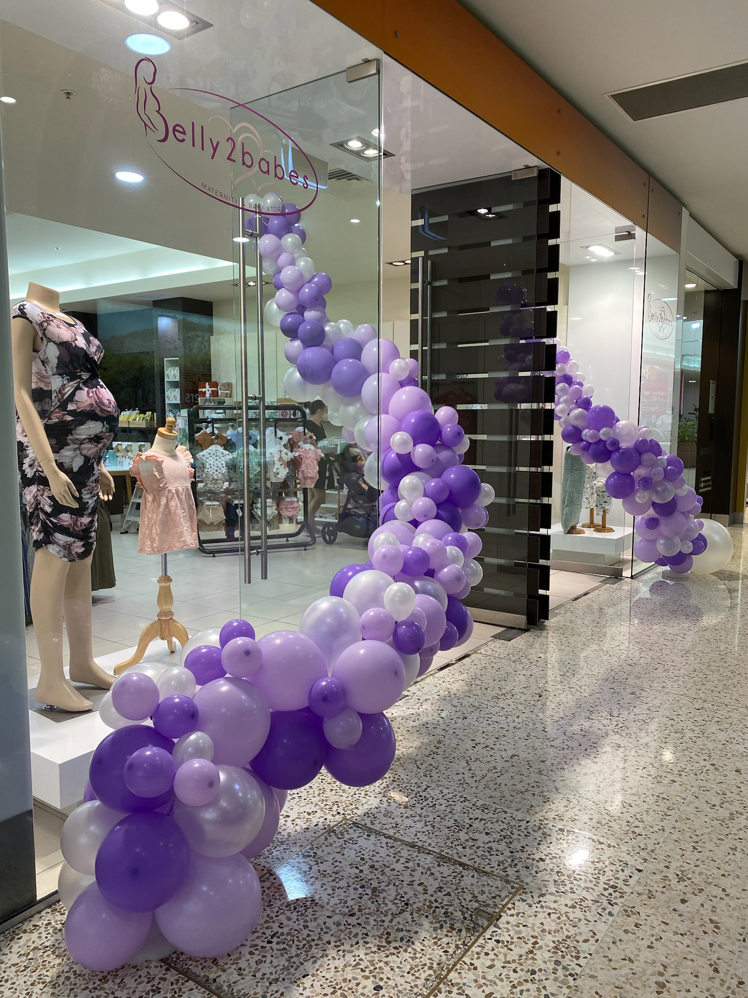 Storefront decorated with purple and white balloons for Jelly2Babe maternity and baby store.