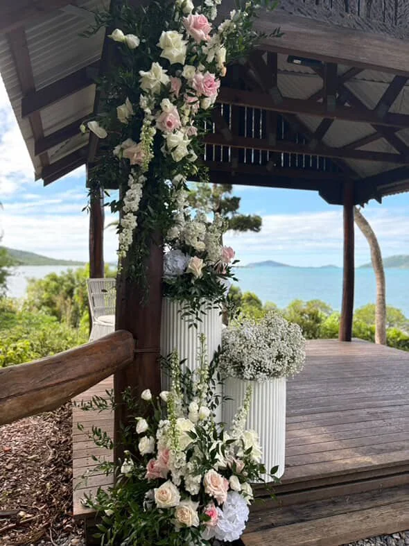 Decorated outdoor pavilion with flowers and a view of the ocean and distant islands.