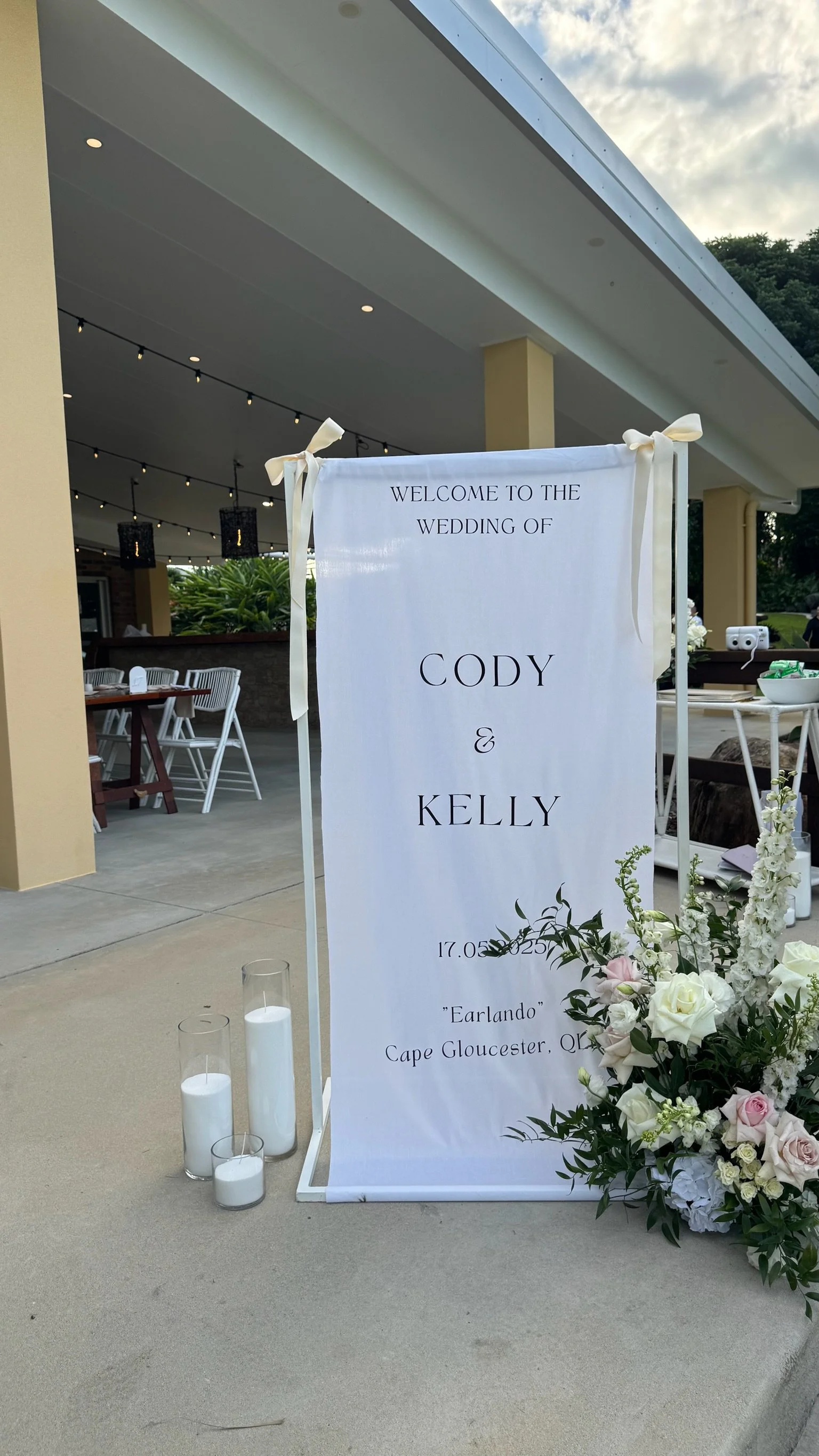 Wedding welcome sign for Cody and Kelly with floral arrangements and candles at the entrance.