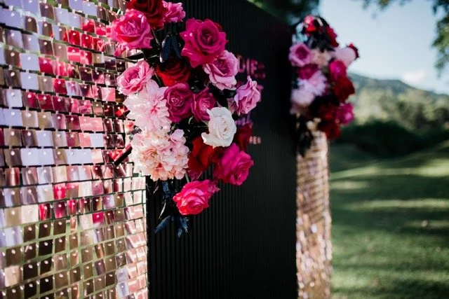 Decorative floral arrangements with pink, red, and white flowers on a black backdrop outdoors.