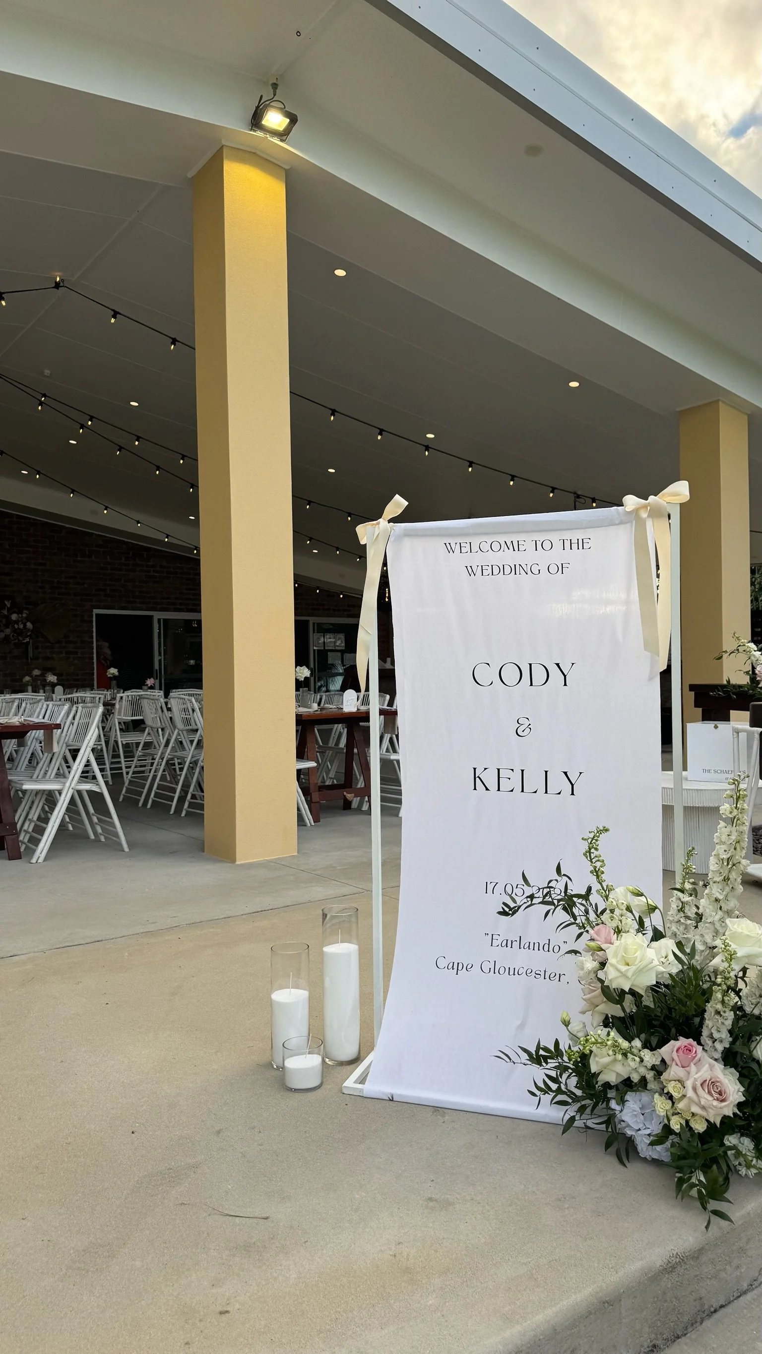 Wedding sign with flowers and candles outside reception area.