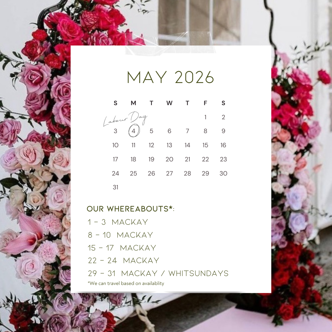 A calendar for May 2026 with handwritten notes for Labour Day on May 4th and travel dates to Mackay. The calendar is overlaid on a backdrop of pink and red roses with some greenery.
