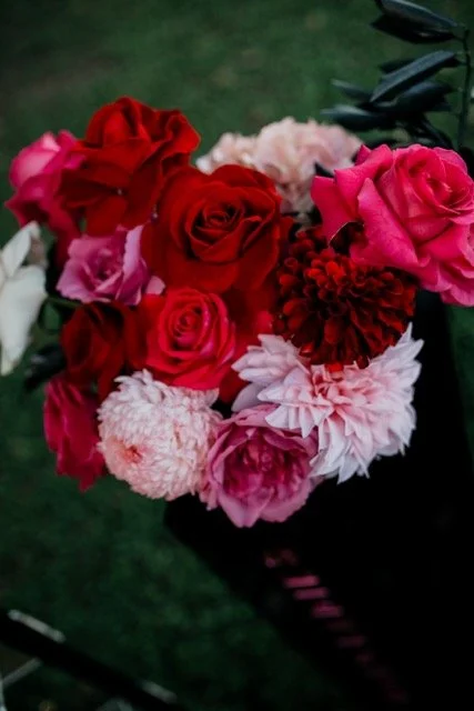 Close-up of a bouquet of red, pink, and white roses and carnations on a dark background.