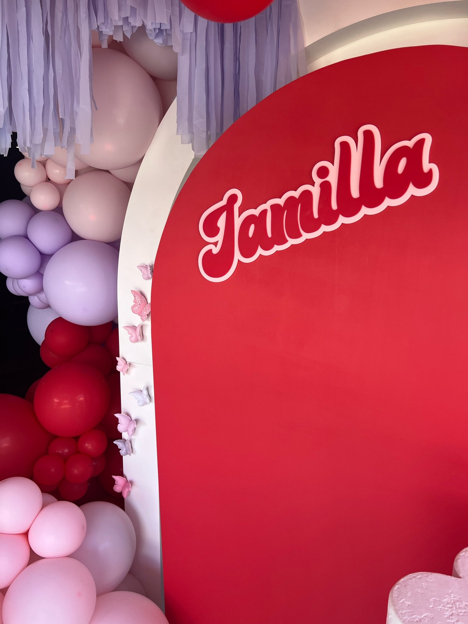 Decorative display with pink, red, and purple balloons and a red sign with the word 'Jamaica' in white cursive.