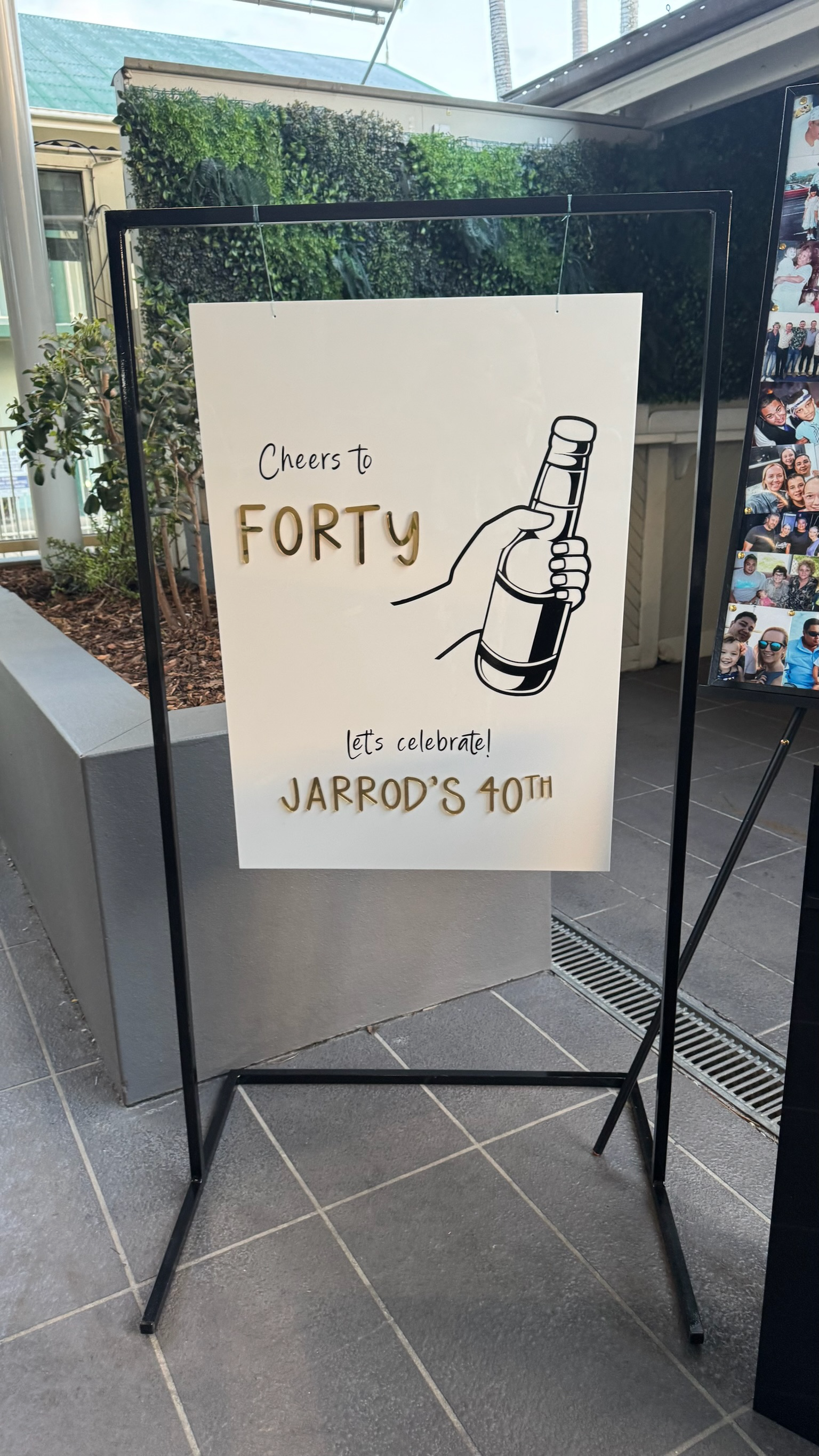 Celebratory sign with a hand holding a beer bottle, reading "Cheers to FORTY, let’s celebrate! JARROD’S 40TH."