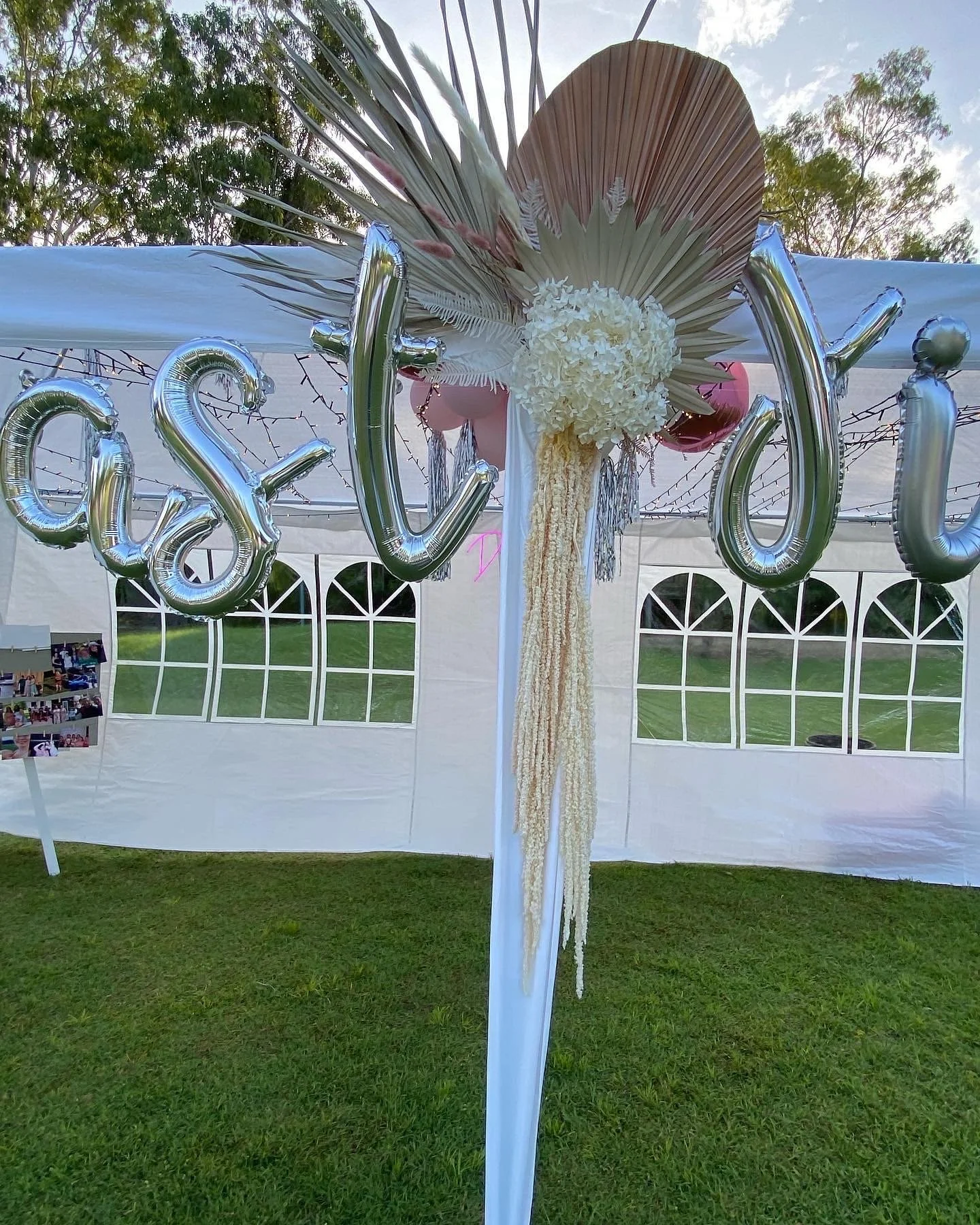 Decorative balloon display spelling 'Love' with floral arrangement in an outdoor event tent.