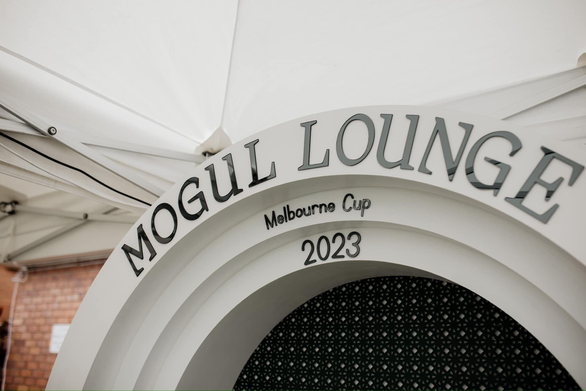Sign for Melbourne Cup 2023 at a Melbourne lounge with a white arch and patterned black interior.