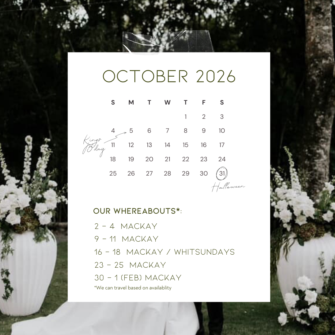 A white calendar for October 2026 with handwritten notes, placed over a background of floral arrangements in white vases at an outdoor event.