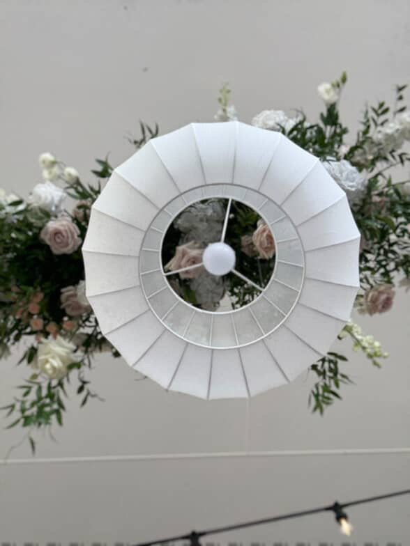A ceiling light fixture oriented upside down, with a flower arrangement behind it.