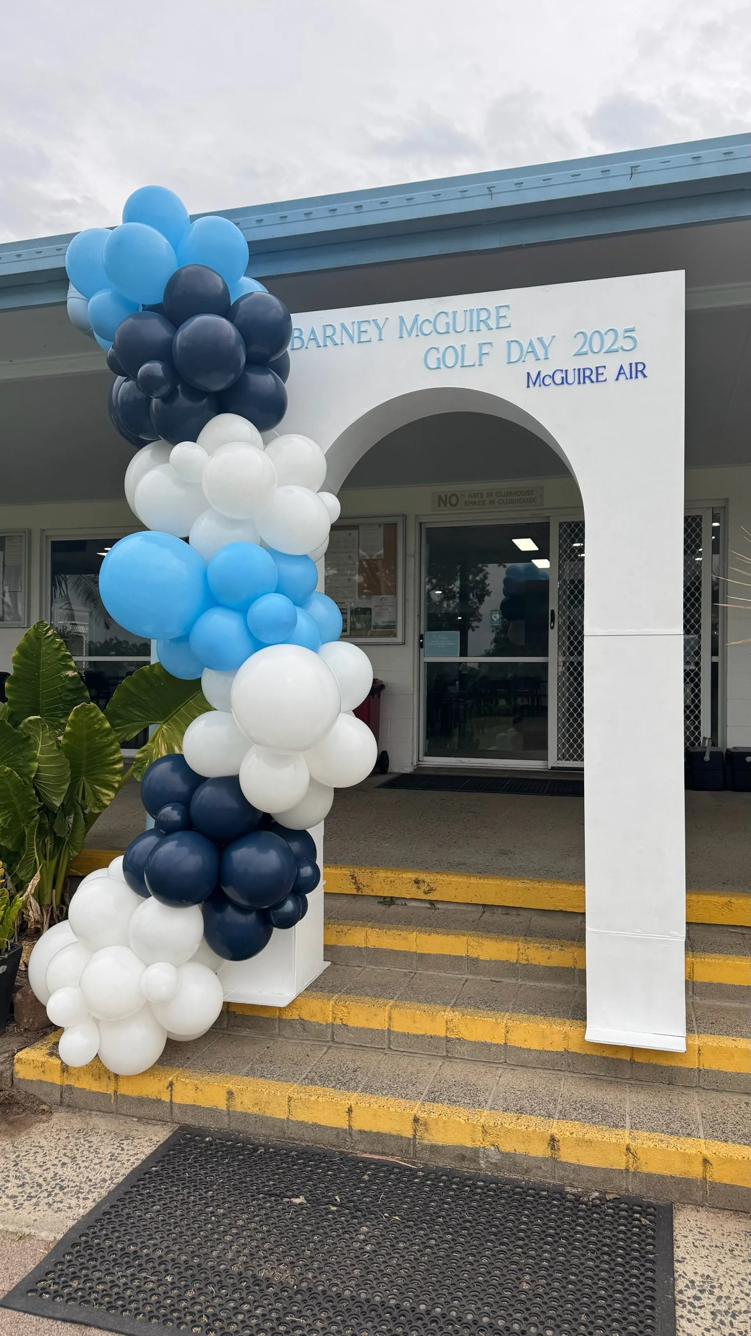 Balloon arch in blue, navy, and white at the entrance of a clubhouse for Barney McGuire Golf Day 2025, sponsored by McGuire Air.