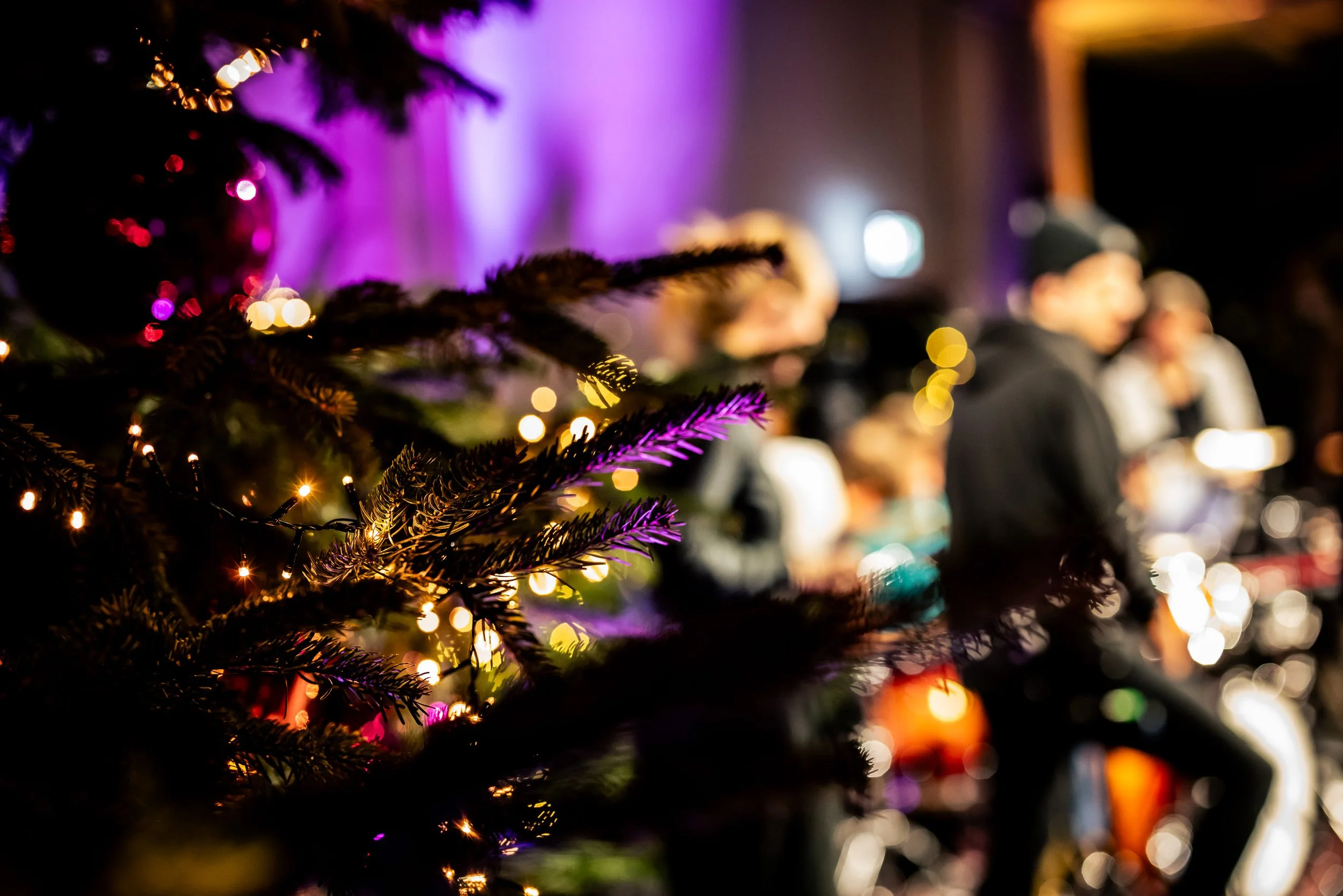 Musiker*innen im Hintergrund auf einer weihnachtlich geschmückten Bühne.