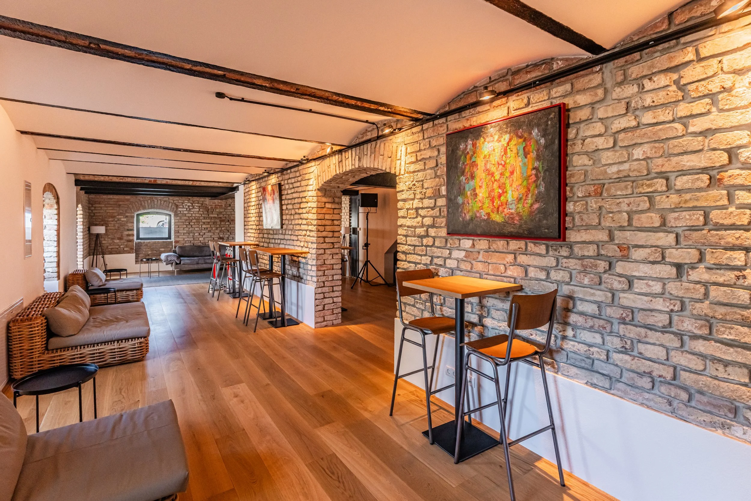 Gemütliche Kaffee- oder Lounge-Bar mit Wänden aus Backstein, Holzboden, moderner Kunstwerke, Sitzgelegenheiten und Stehtischen.