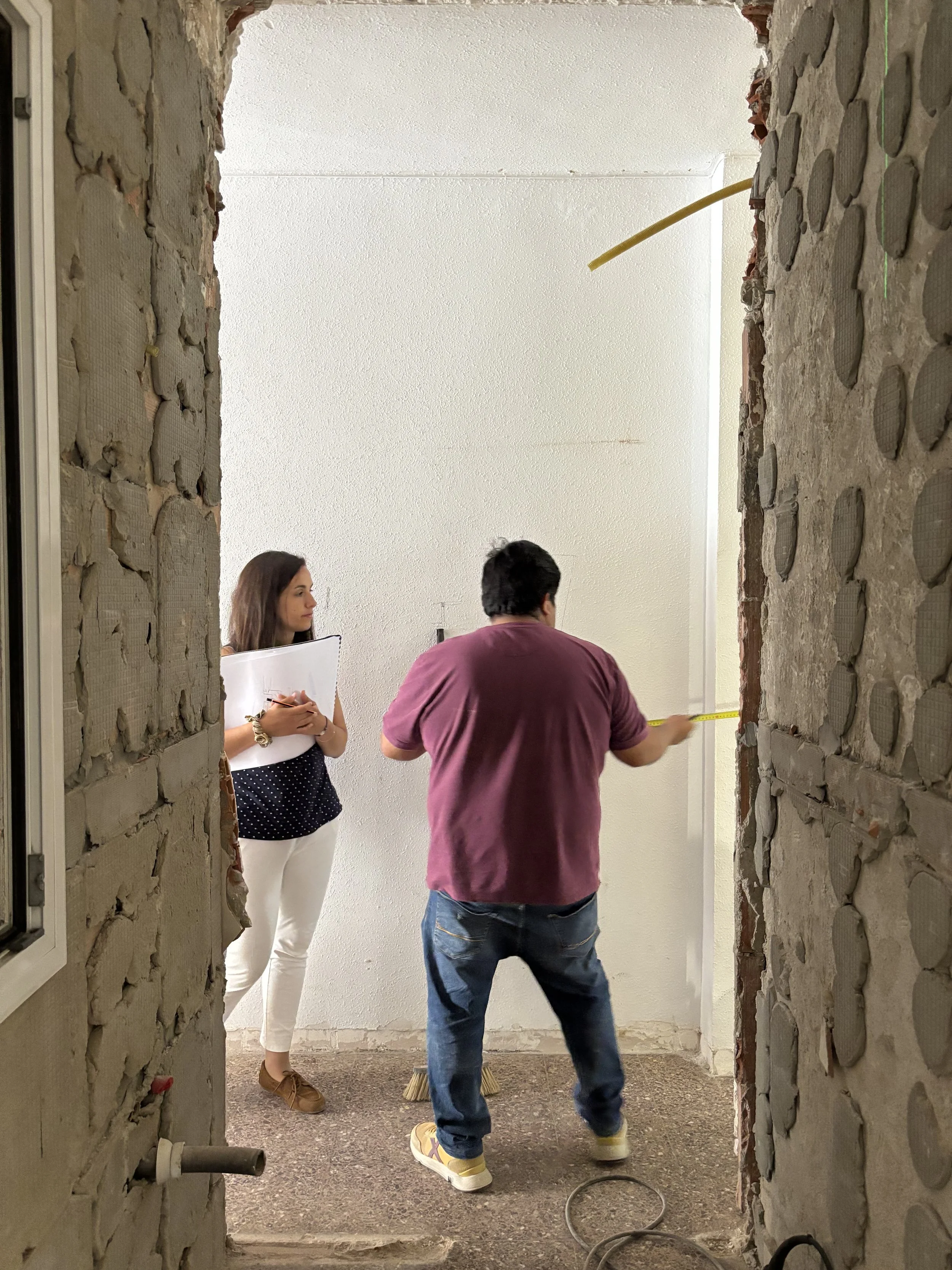 Técnicos realizando mediciones y revisando el proyecto durante la inspección de una vivienda en proceso de reforma