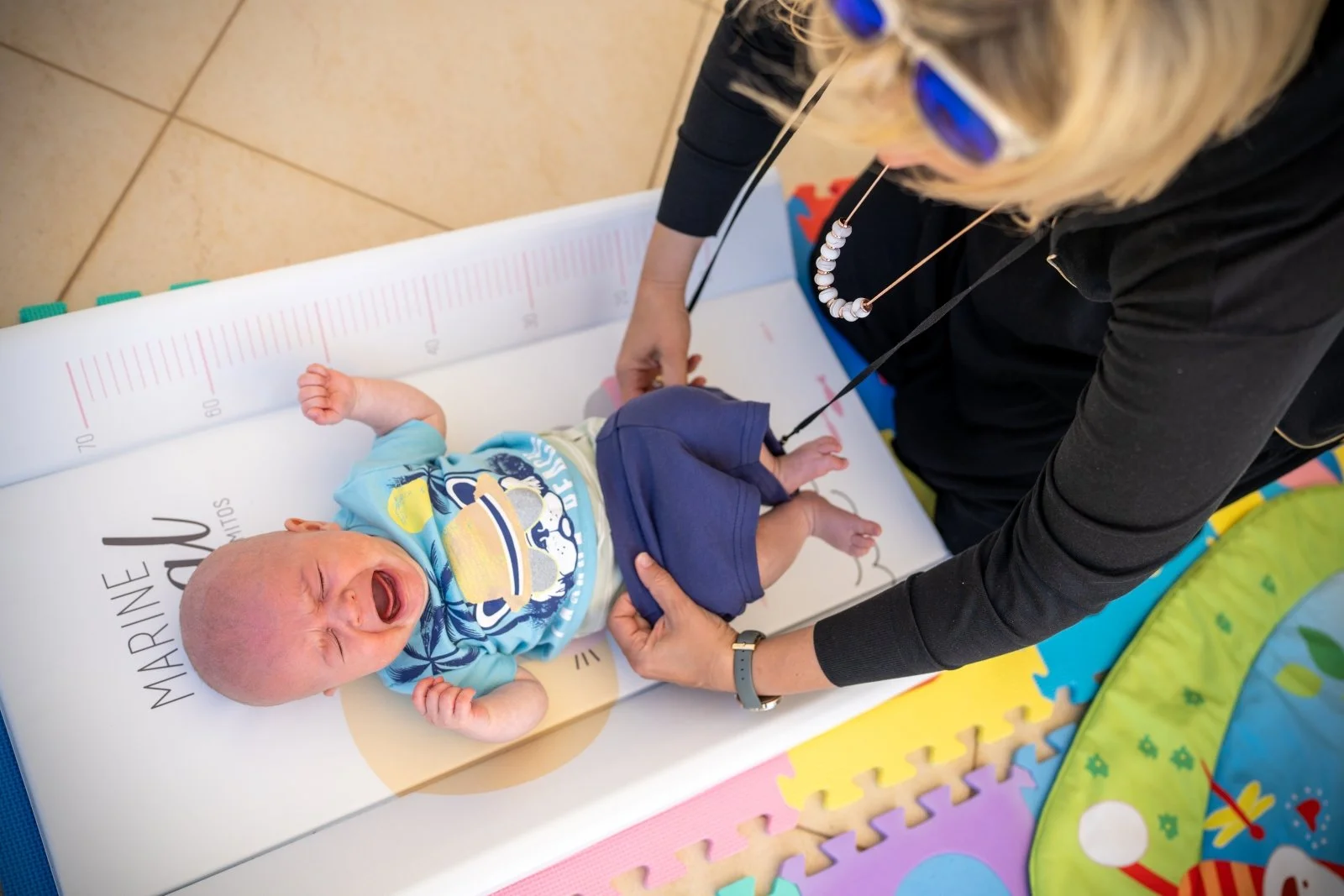 Baby cries while his mom changes his diaper by Michelle Molnar Photography