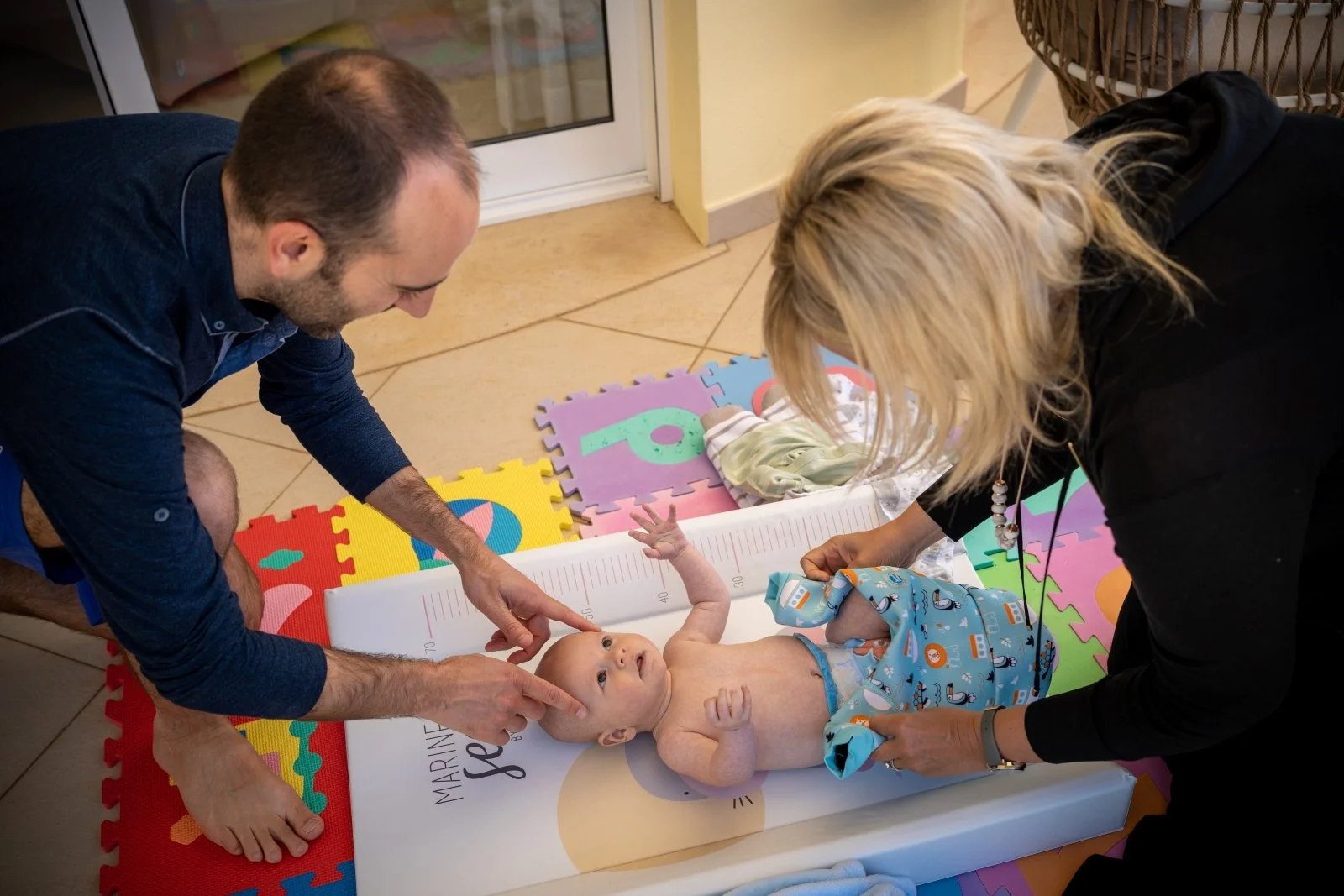 mom and dad get baby dressed on a floor mat.
