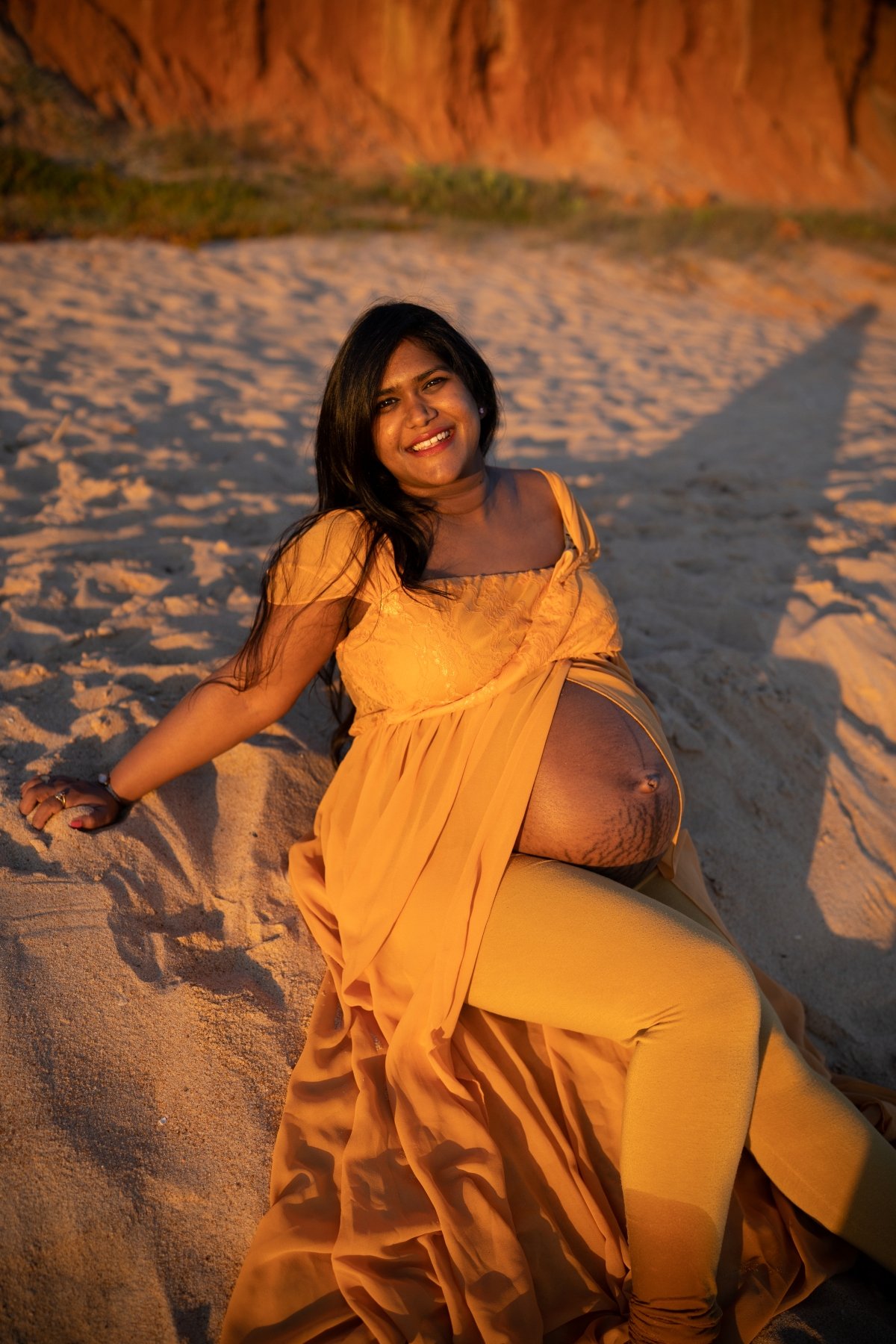 woman in orange on beach during a San Diego Maternity session