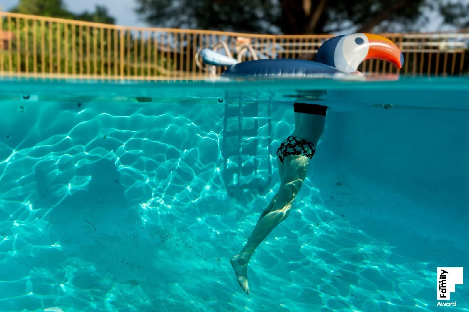 Award-winning underwater photo by Tucson family photographer Michelle Molnár shows a child in floral swimsuit swimming below the pool surface.