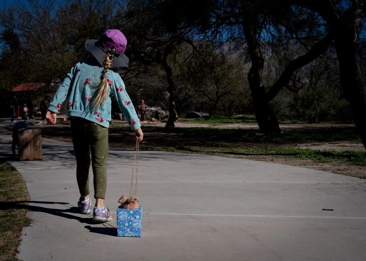 girl dragging stuffed animals outside in a Tucson family photography session.