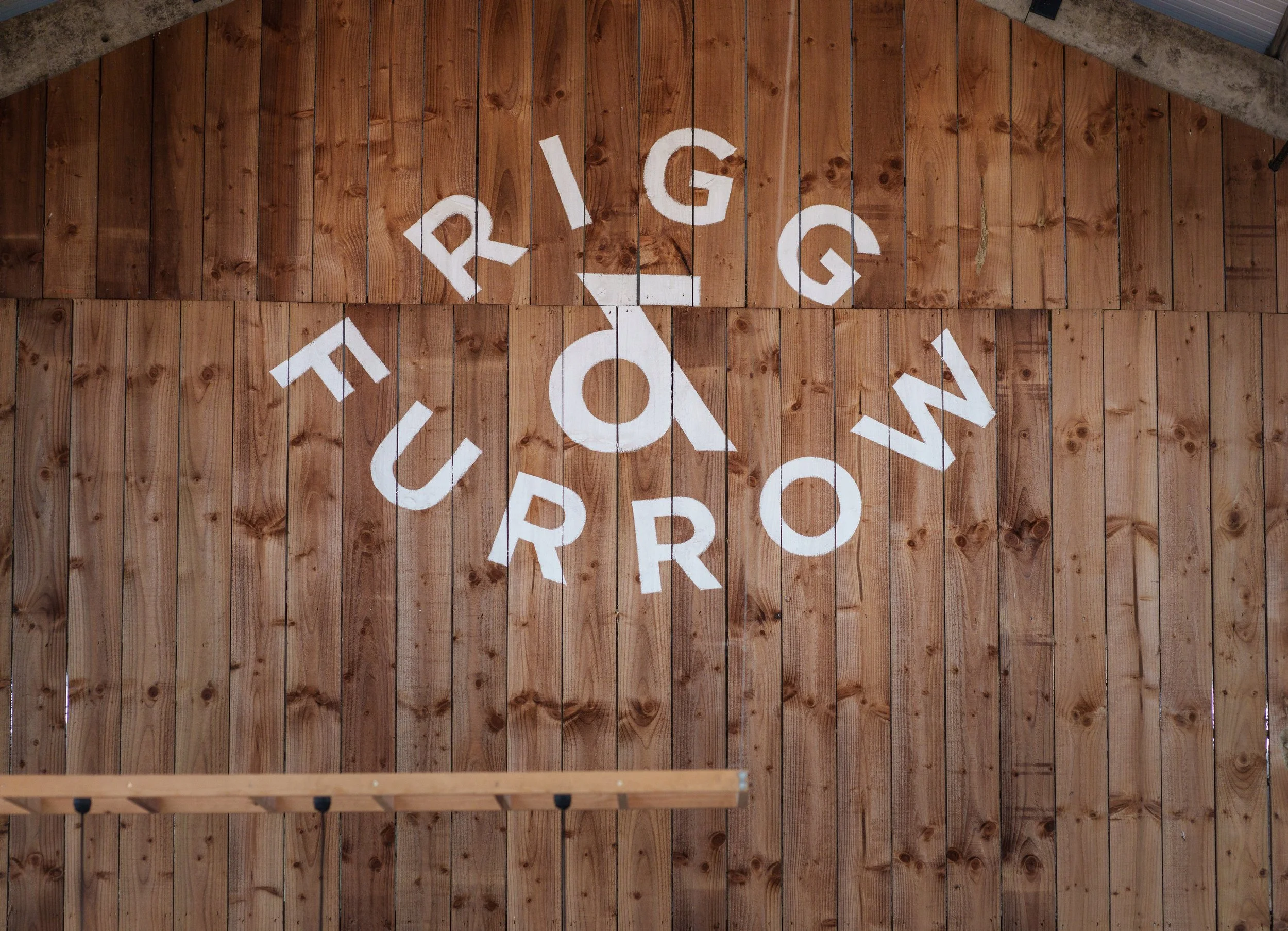 Wooden wall with the words "Rigg & Furrow" painted in white.