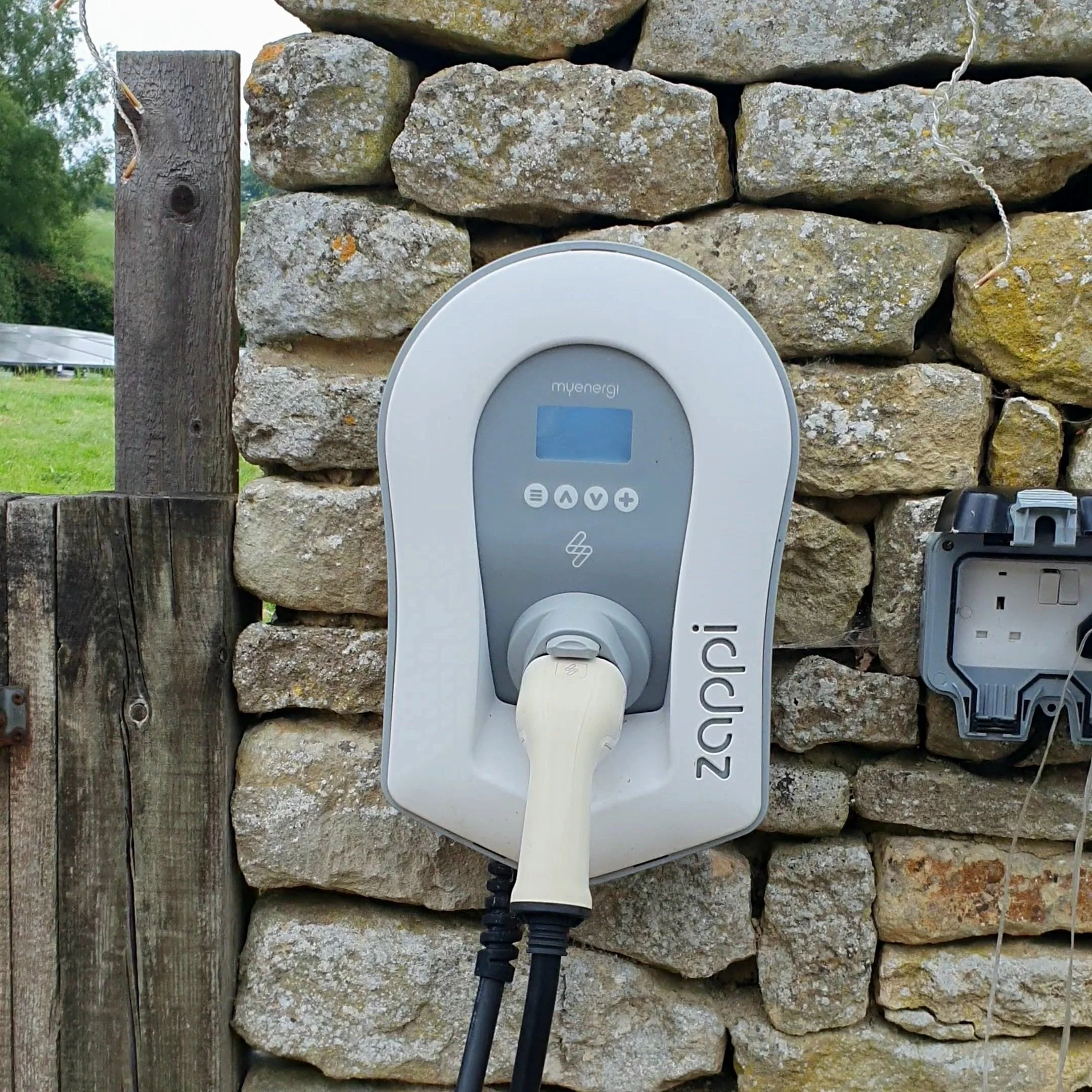 White Myenergi Zappi EV Charger installed on a stone wall