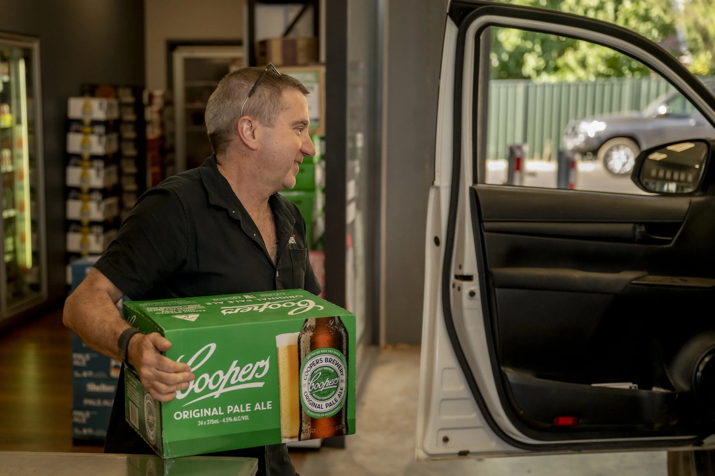 Brew Plus team member loading Coopers Pale Ale into a customer’s vehicle at the Busselton liquor and coffee drive-thru