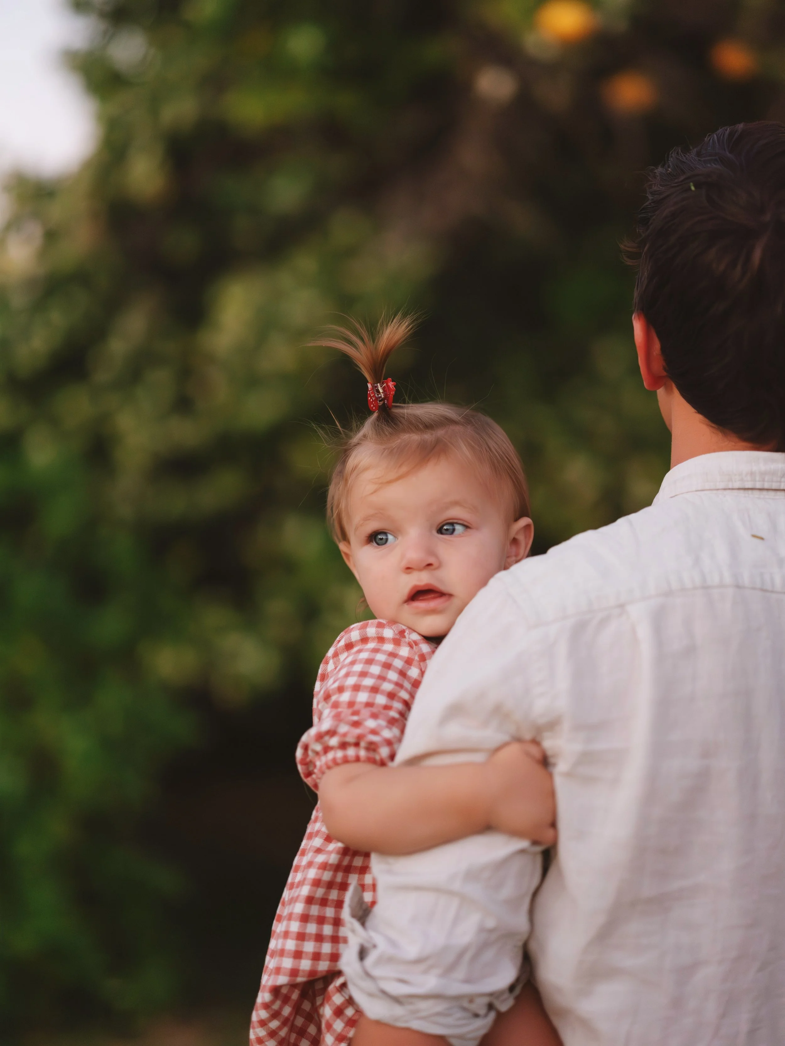 A man holding a young girl with a surprised expression on her face outdoors.