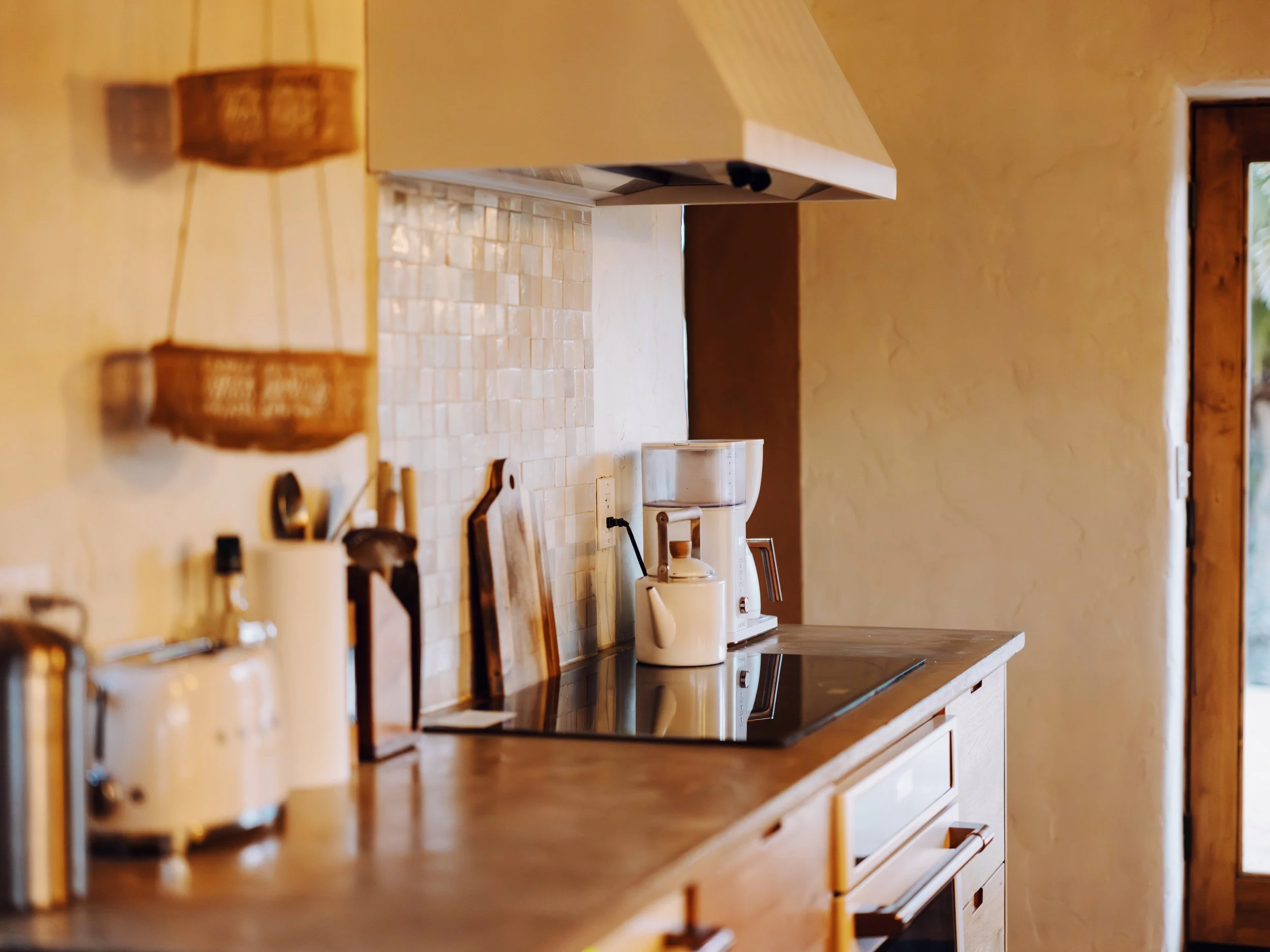 Kitchen with wooden cabinets, beige tiled backsplash, coffee machine, and a window with a view outside.