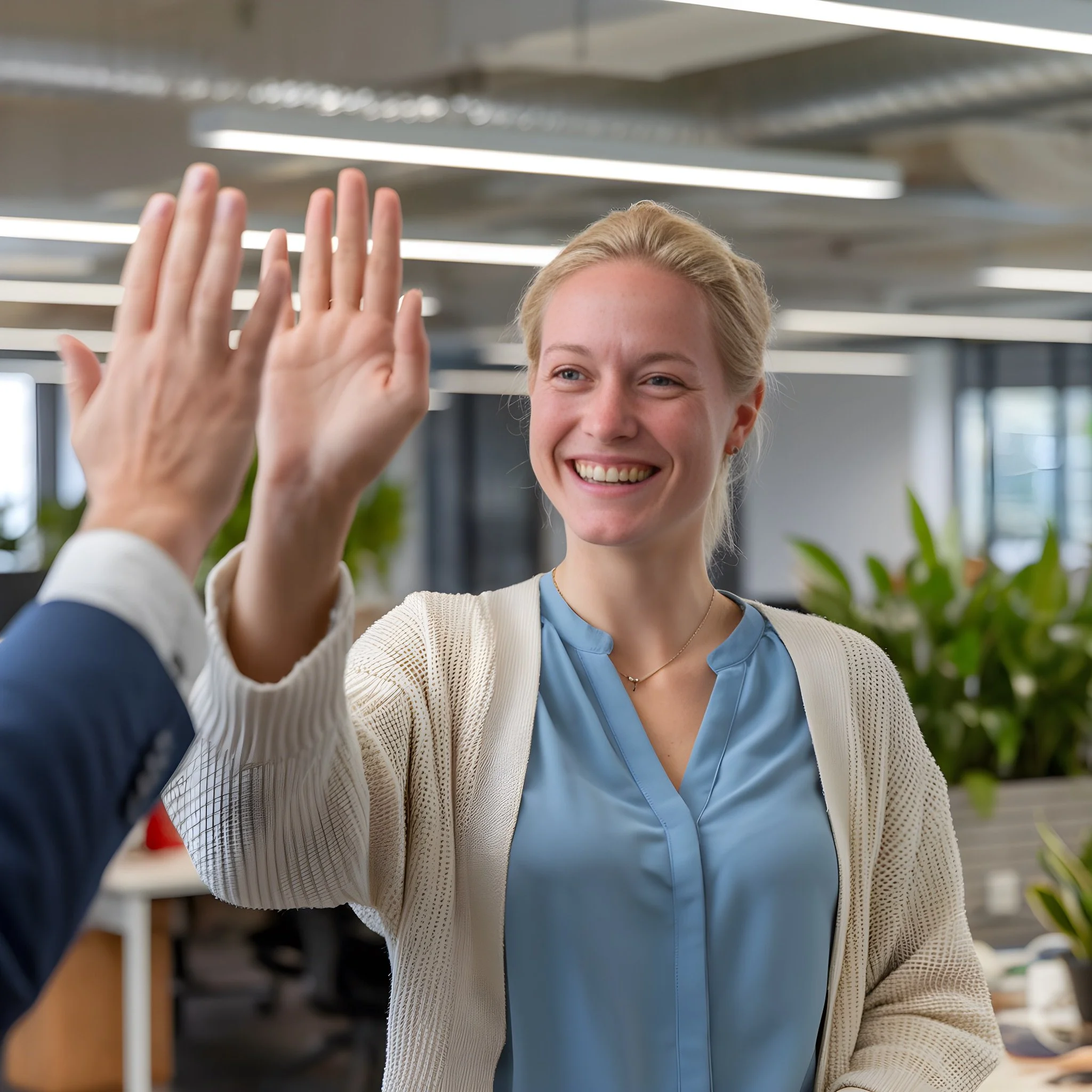 A smiling office worker giving a high-five in a bright, modern workspace. This image symbolizes team success and positive workplace culture, emphasizing the benefits of "Get DeskFit" programs for improving employee wellness and morale.