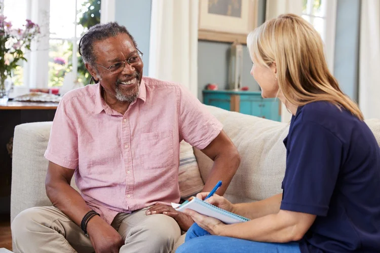 A healthcare professional speaking with a patient at home