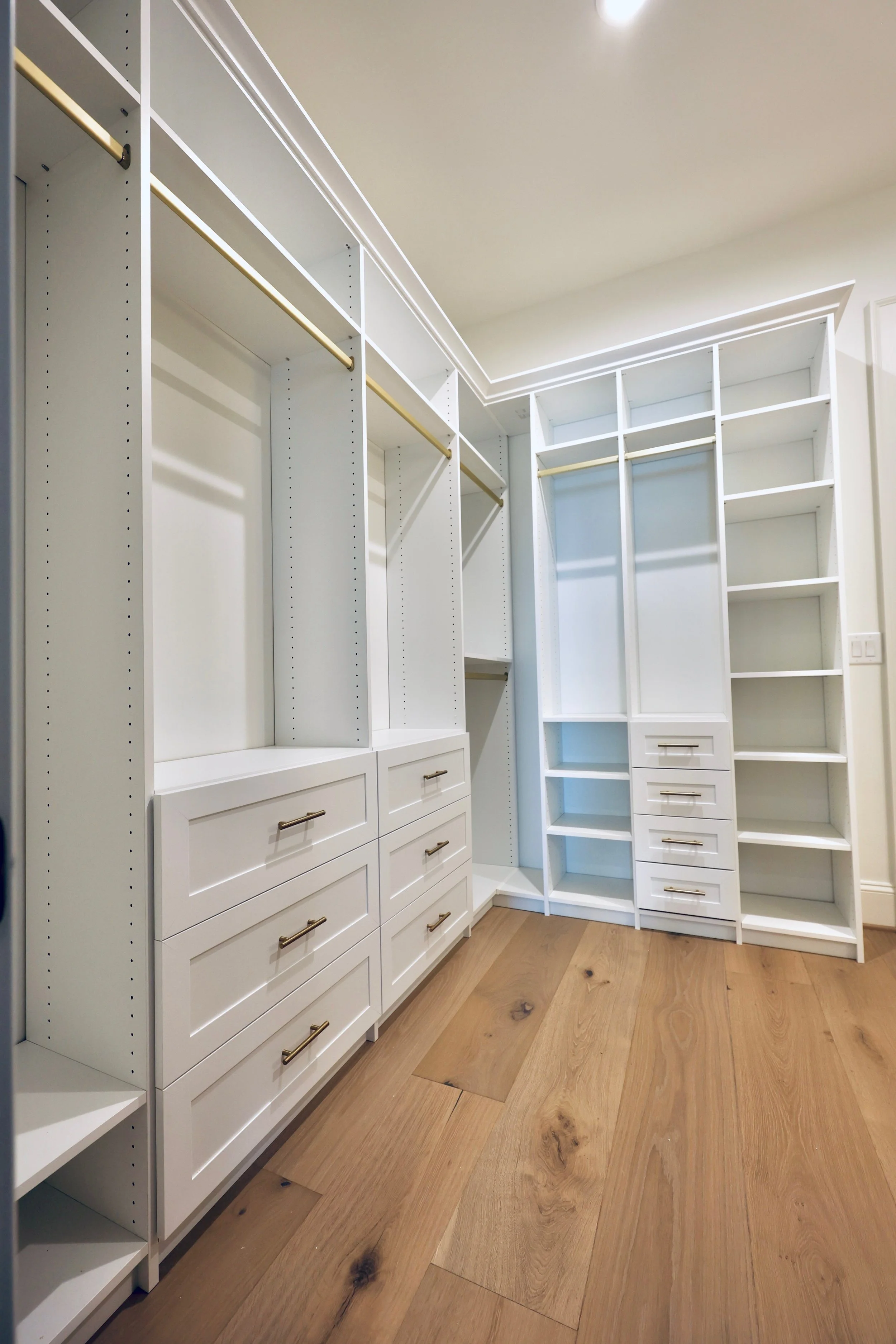 Closet with organized clothing on black shelves and a mirror on black geometric patterned wall.