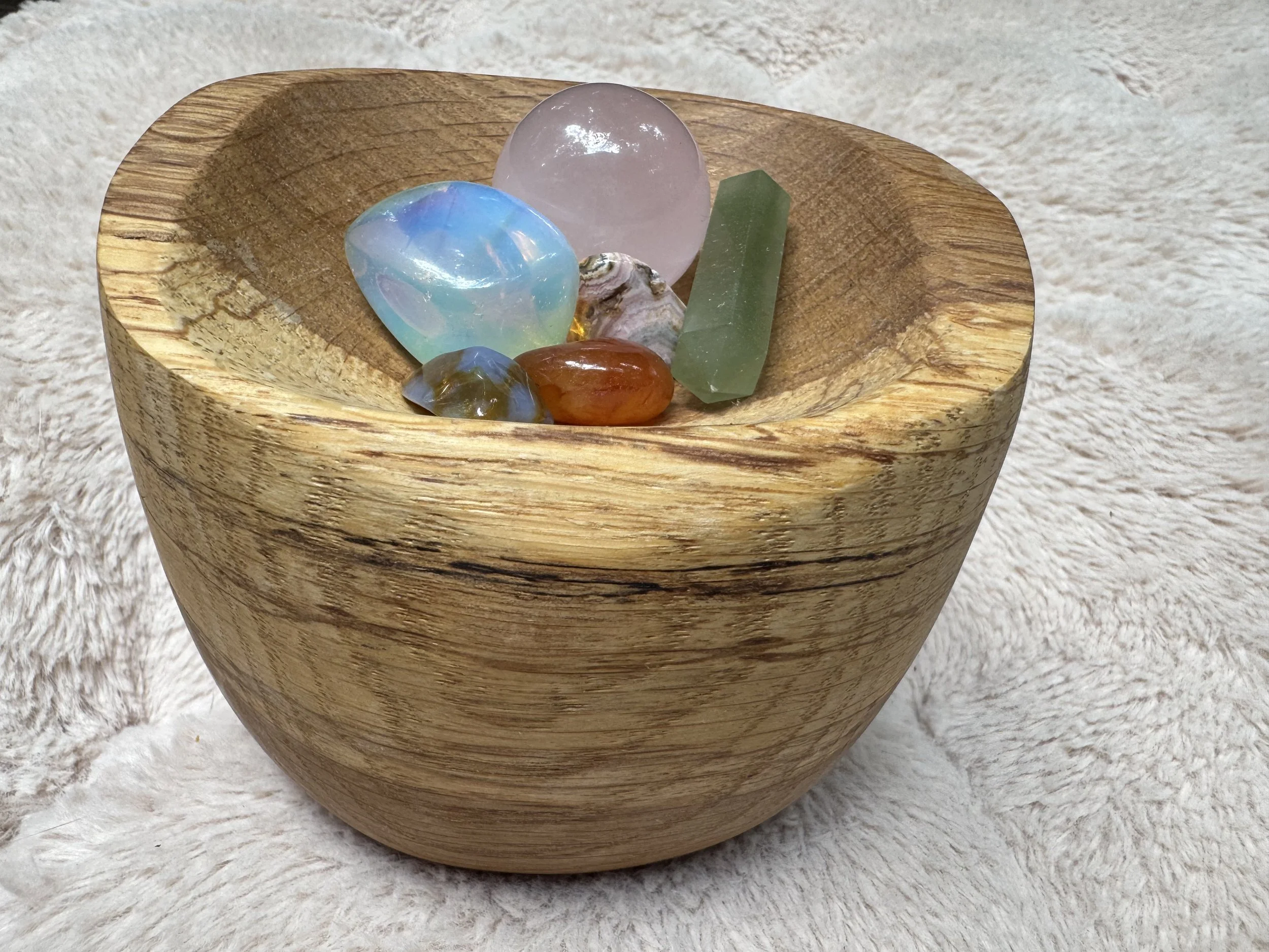 Hand-carved wooden bowl by Tamara Albright with stones and crystals on a soft, warm beige textured background, accompanying the Clarity stage of Allvibe Creative’s Brand Design process.