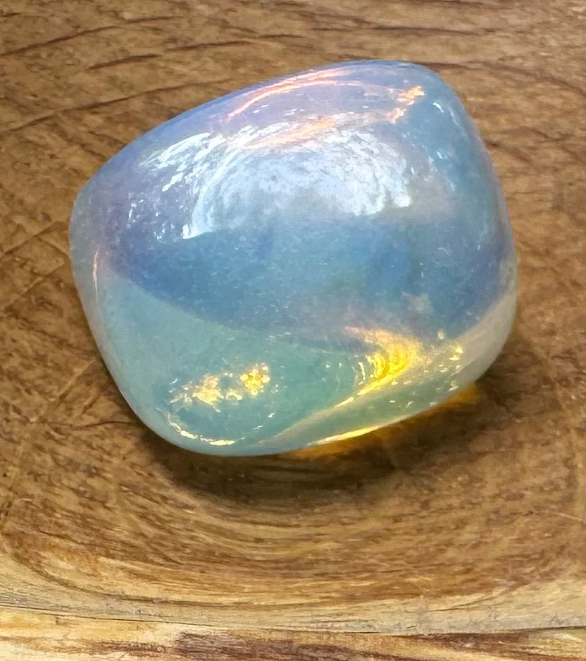 Close-up of an opalite stone reflecting shifting colors within a hand-carved wooden bowl by Tamara Albright, accompanying the Development stage of Allvibe Creative’s Brand Design process.