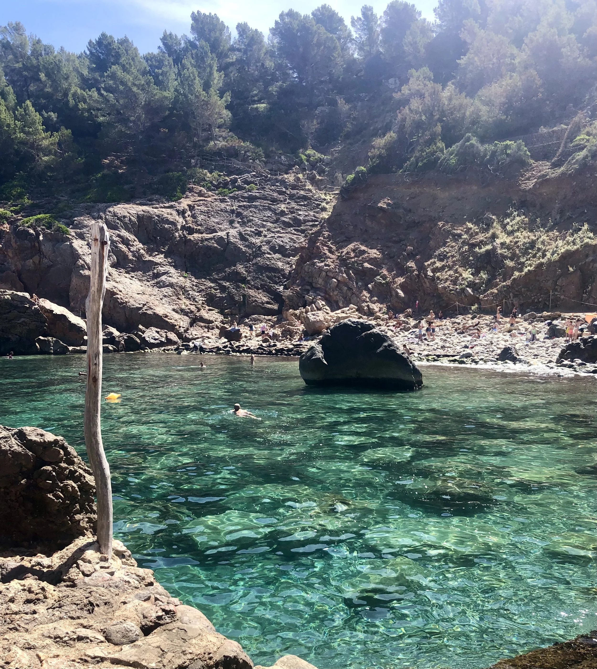 Beautiful turquoise ocean with people swimming, surround by rocks
