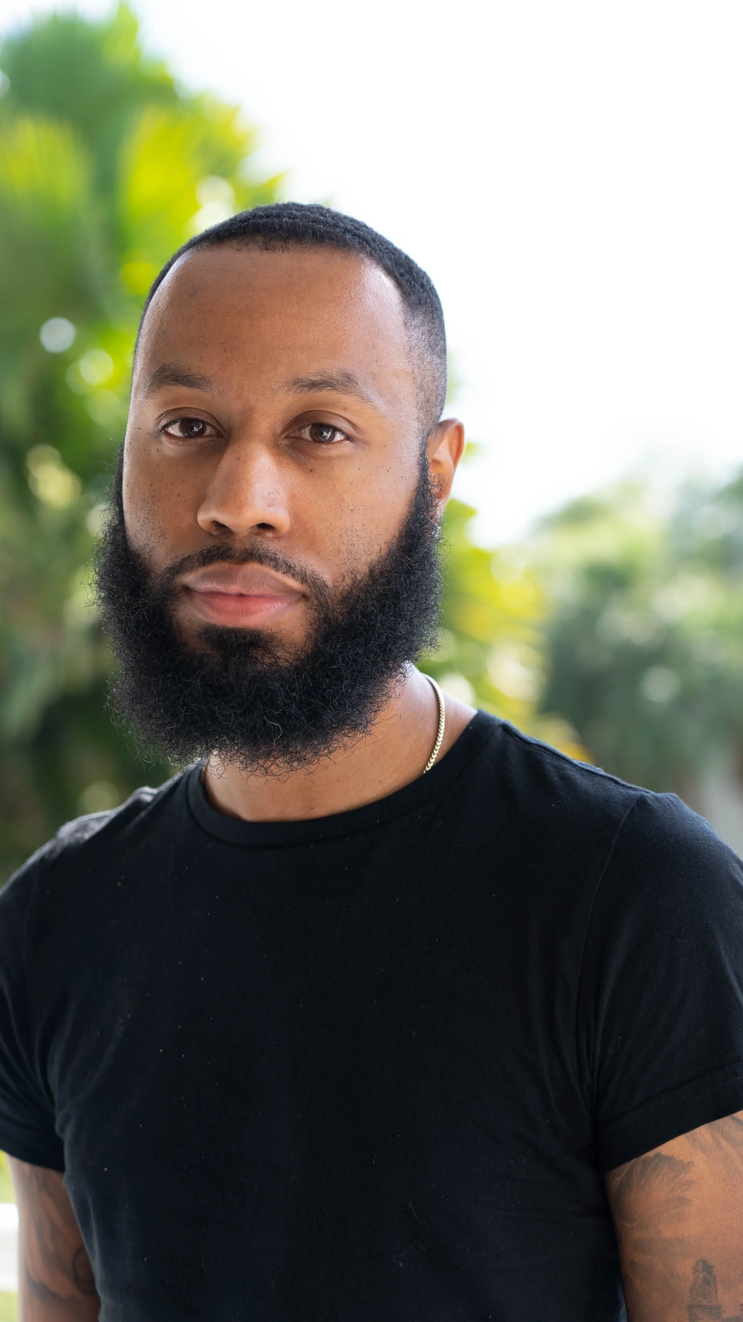 Man with a black beard and black tshirt, nature backgound