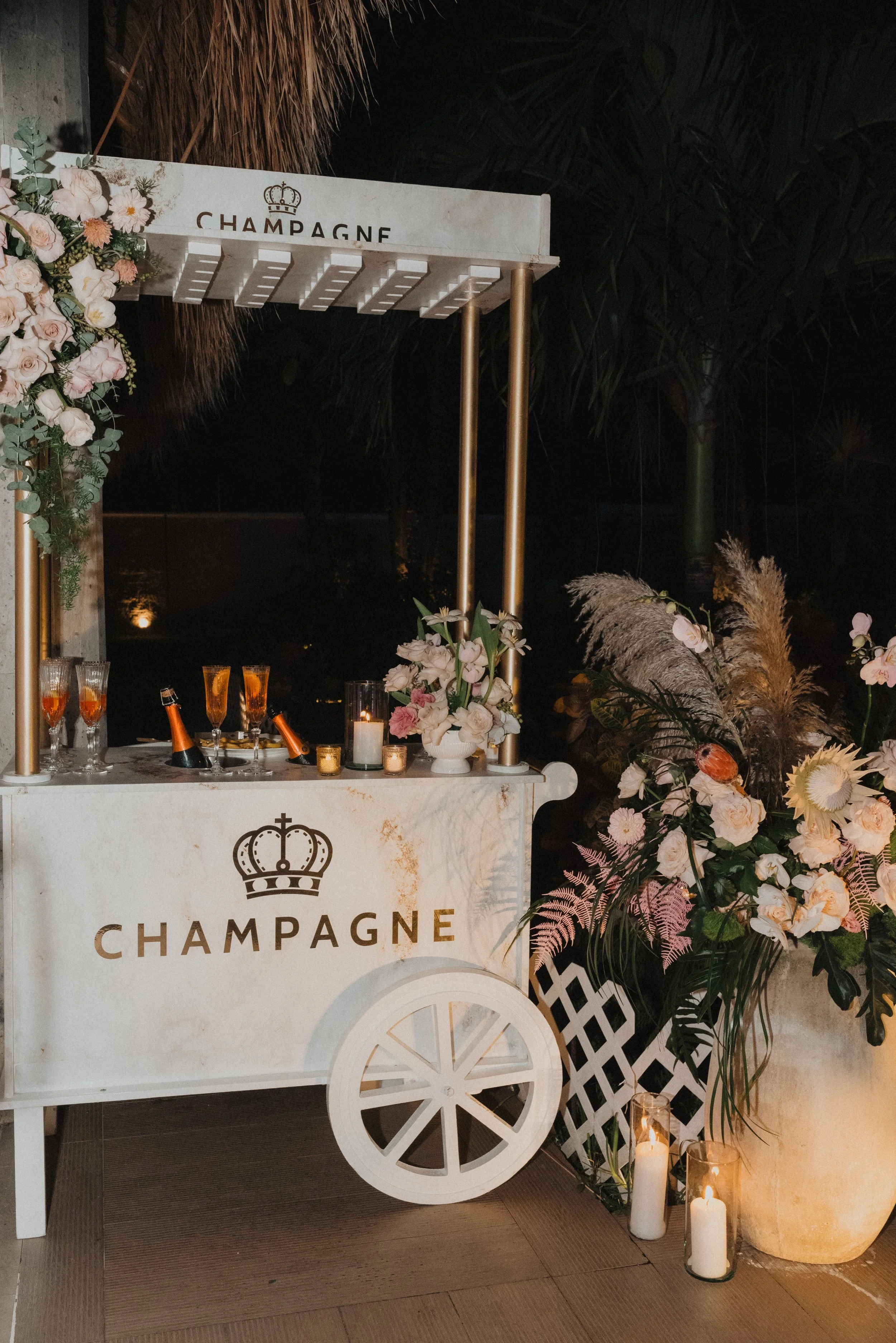 Carroza de champán decorada con flores y velas, en un evento nocturno.