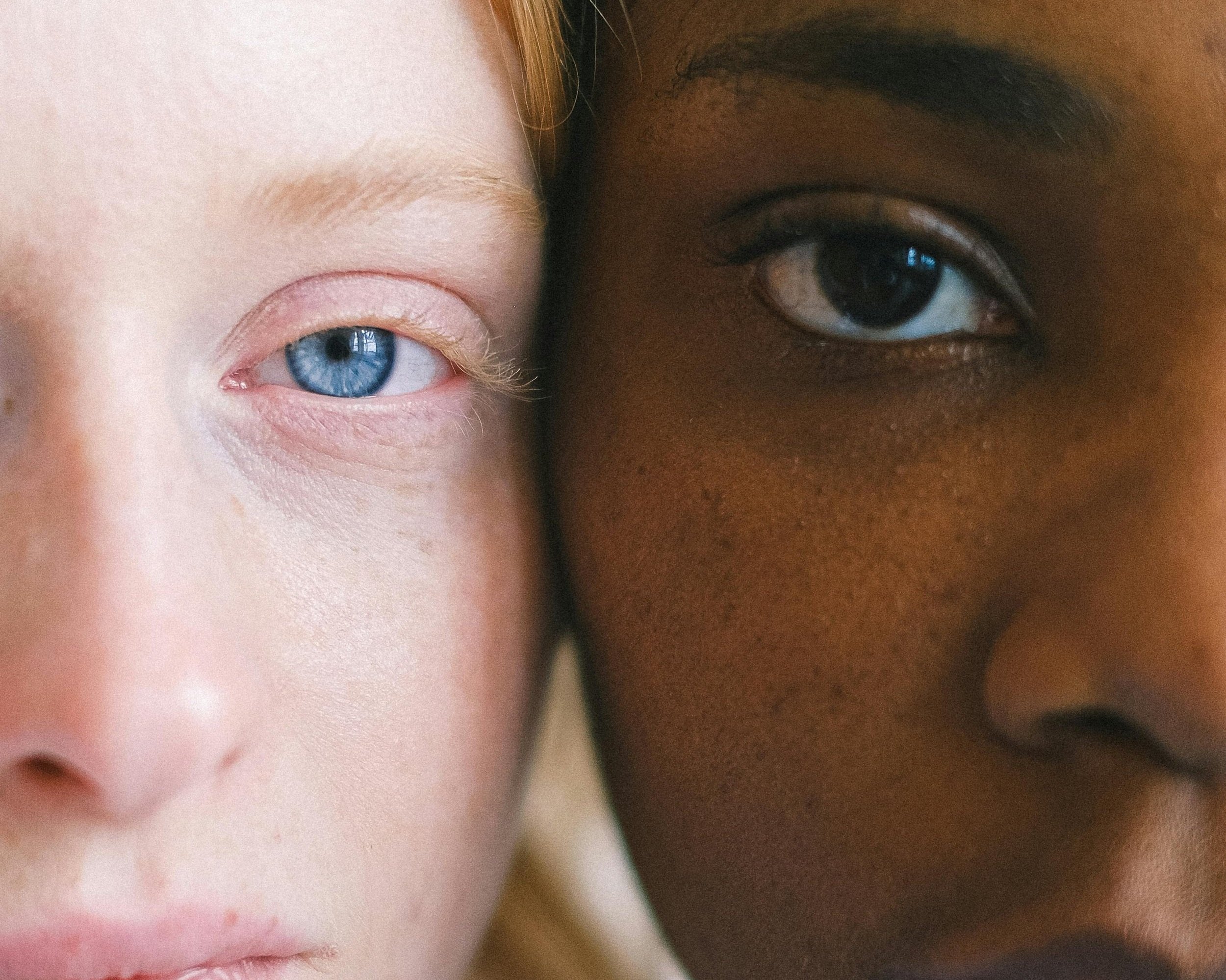 Close-up of two people with different skin tones and eye colors, side by side, focusing on their eyes and faces.
