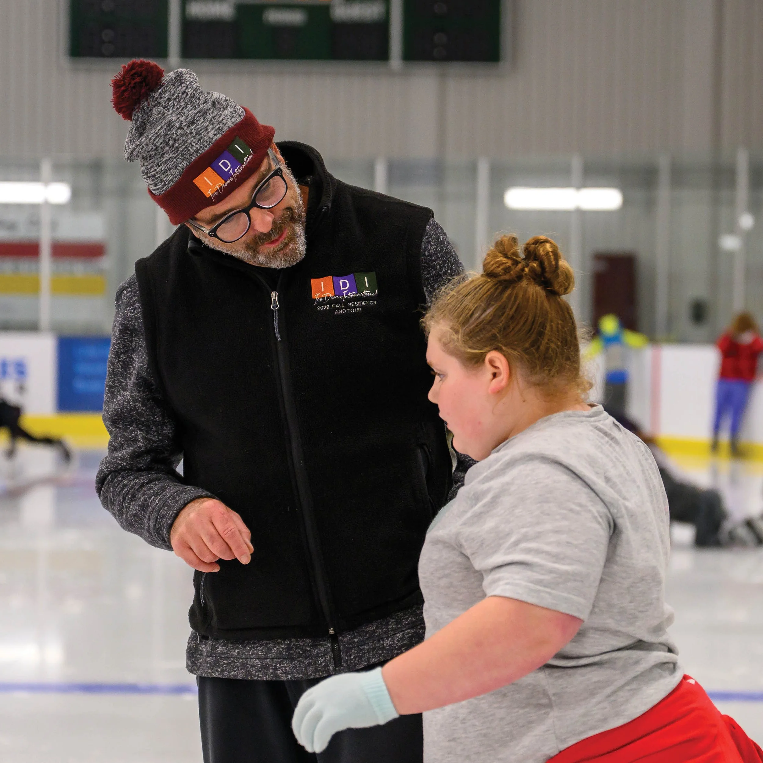 Instructor helping a young girl learn to skate.