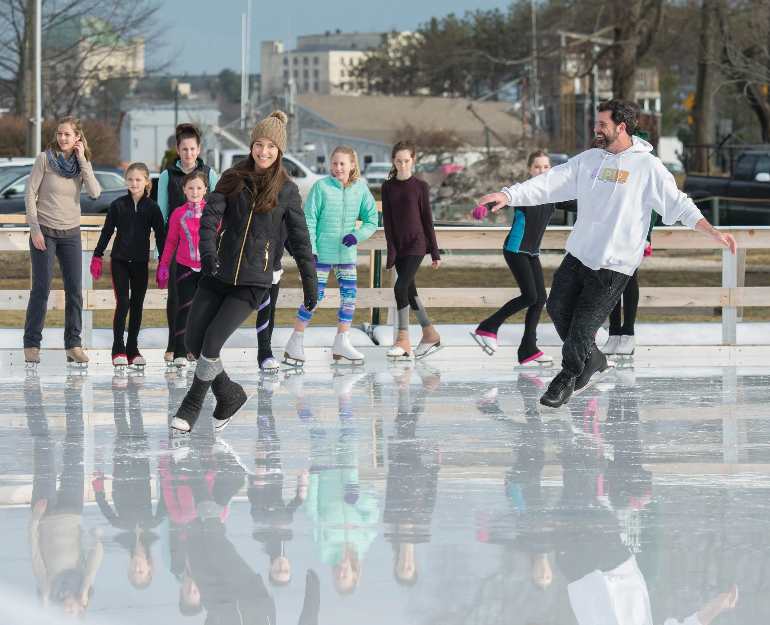 Skaters skating on rink with children looking on.