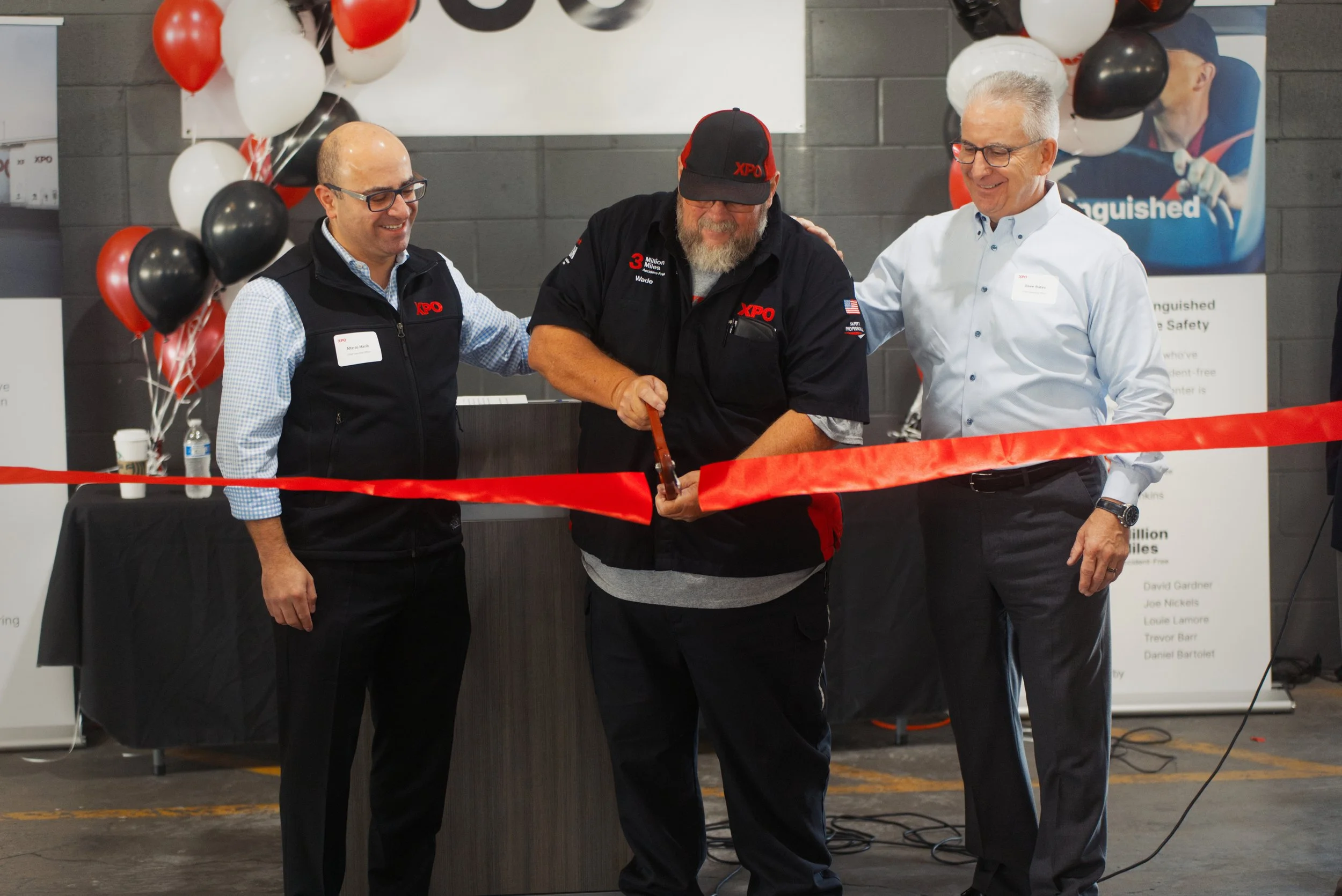 Top executives of a large freight celebrate the grand opening of a new facility with a ribbon-cutting ceremony, captured with professional cameras.