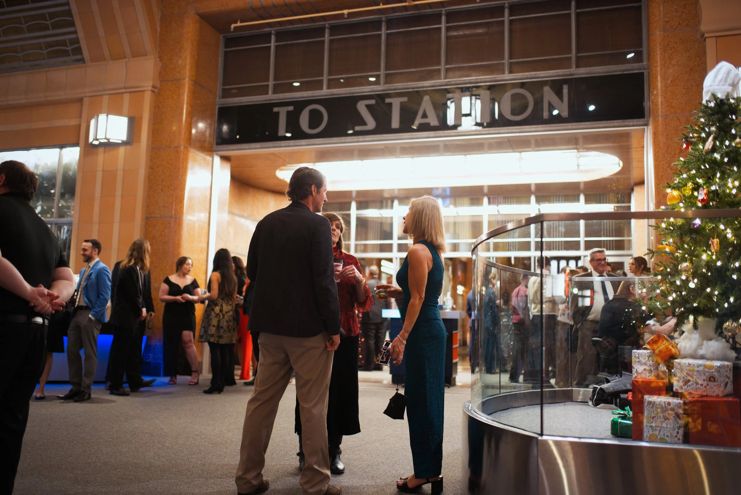 Artistic photo of attendees at corporate holiday party with beautiful lighting inside historic train station venue.